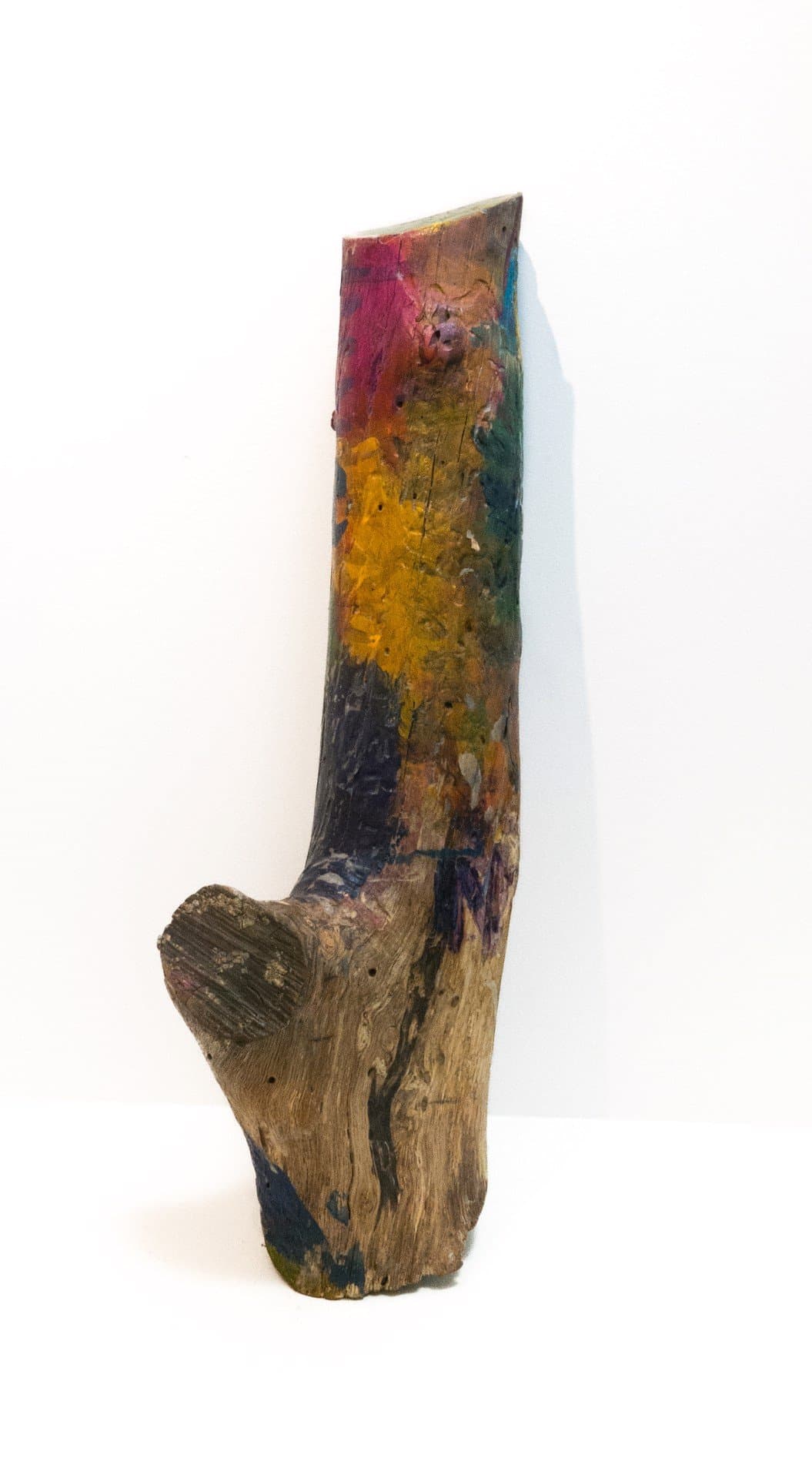 Mixed media sculpture of weathered wood painted with vibrant colors including magenta, yellow, and teal