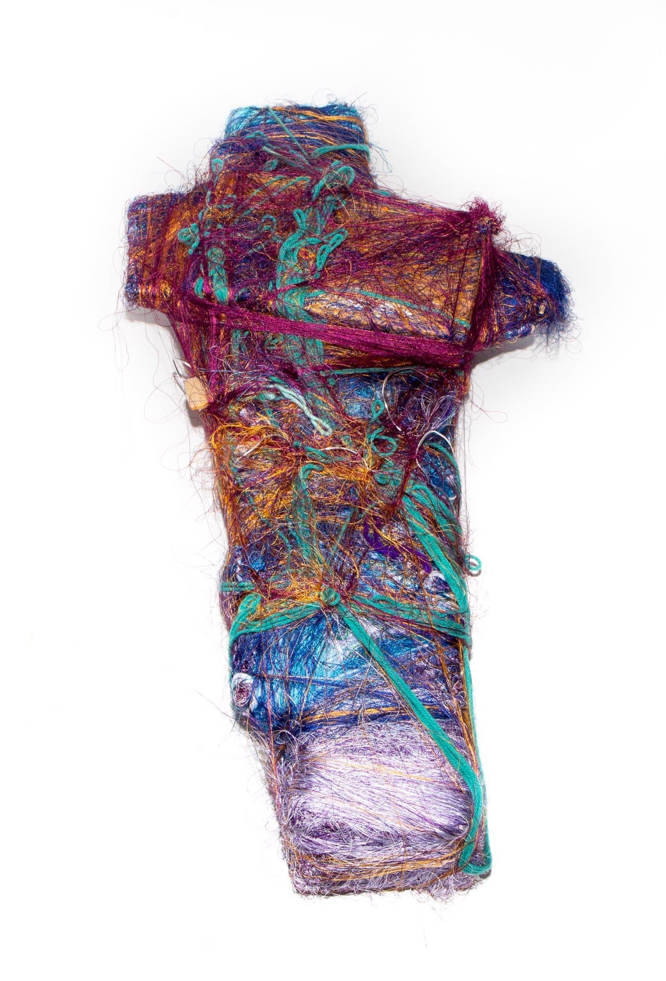 Cross-shaped fiber sculpture with densely wrapped multicolored threads in purple, turquoise, orange, and blue.