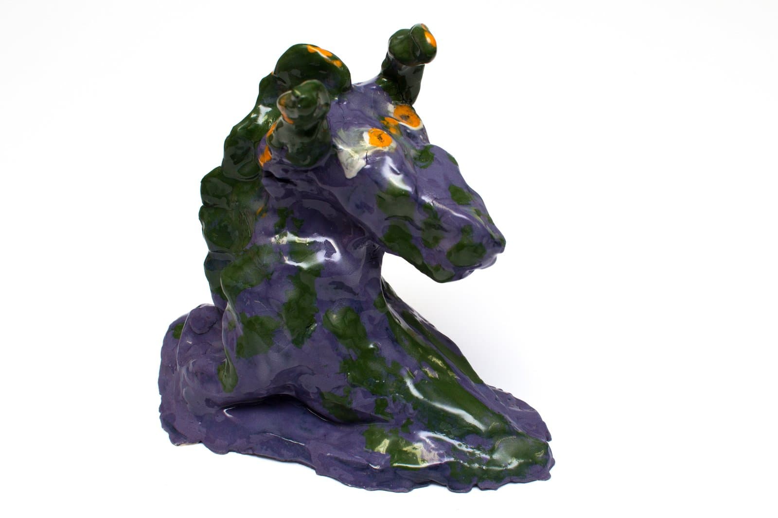 Glazed ceramic sculpture of a seated horse figure in mottled purple and dark green with orange accents.