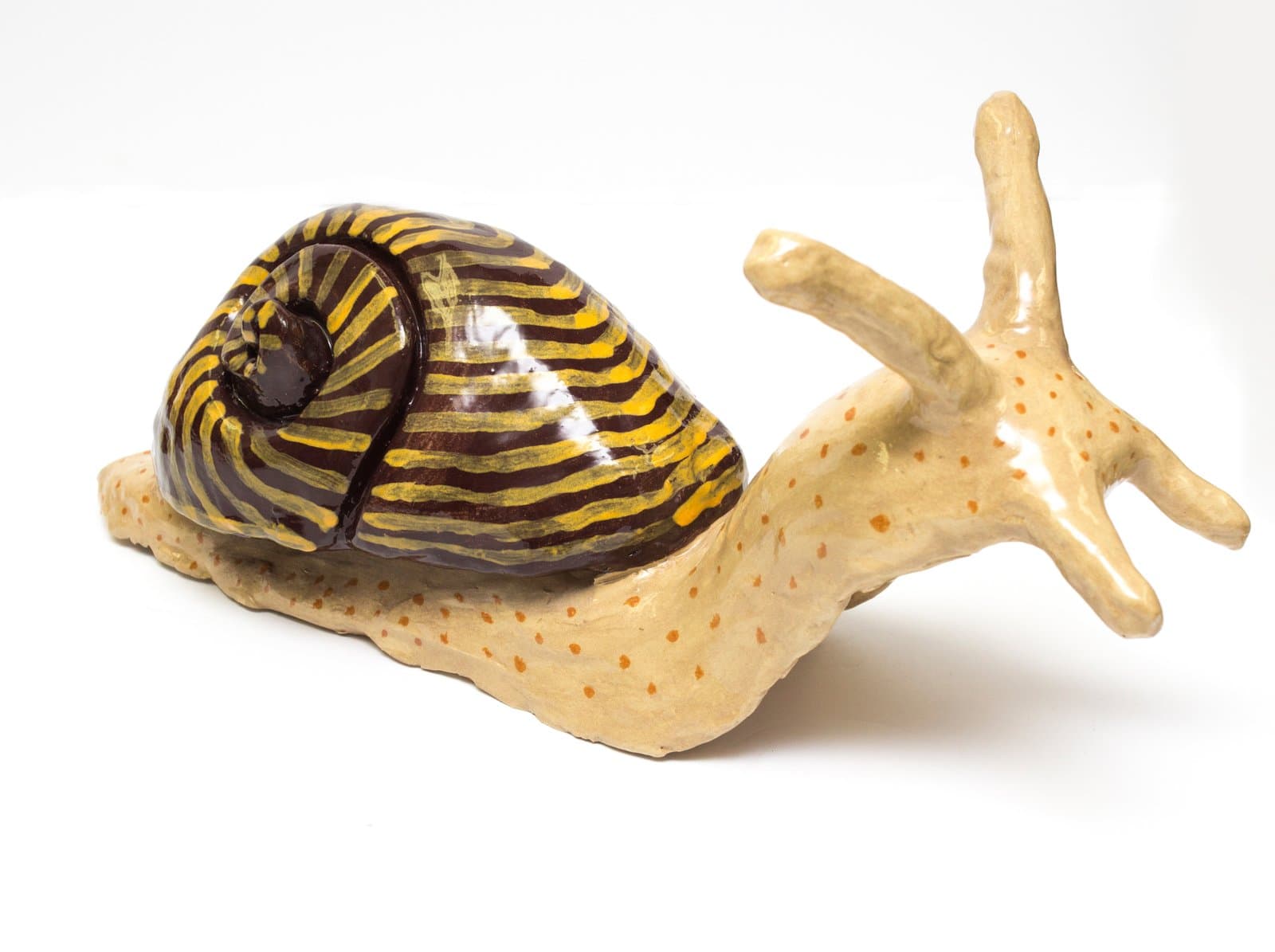 Glazed ceramic sculpture of a snail with a dark brown and yellow striped shell and cream-colored body with orange spots.