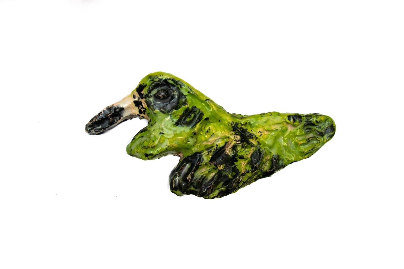 Small ceramic sculpture of a bird form, heavily textured, glazed in bright green and black on a white background.