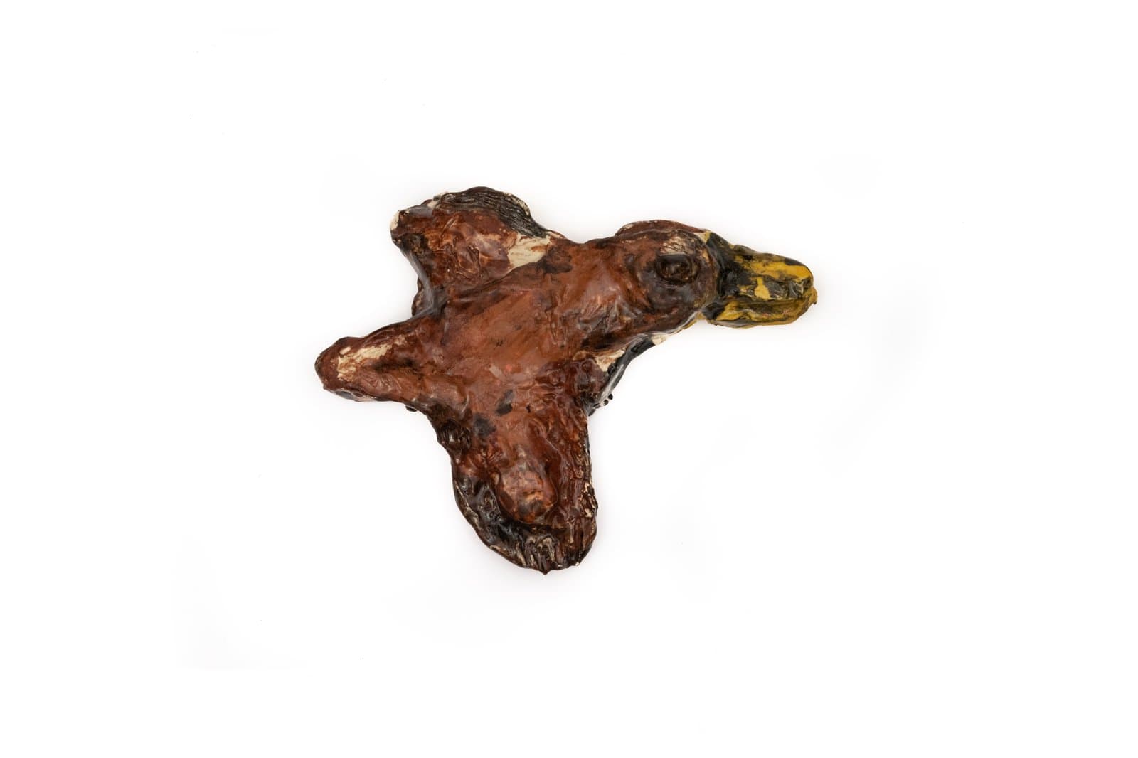 Small ceramic sculpture of a duck in flight, glazed in deep brown with a yellow-green bill, on white background.