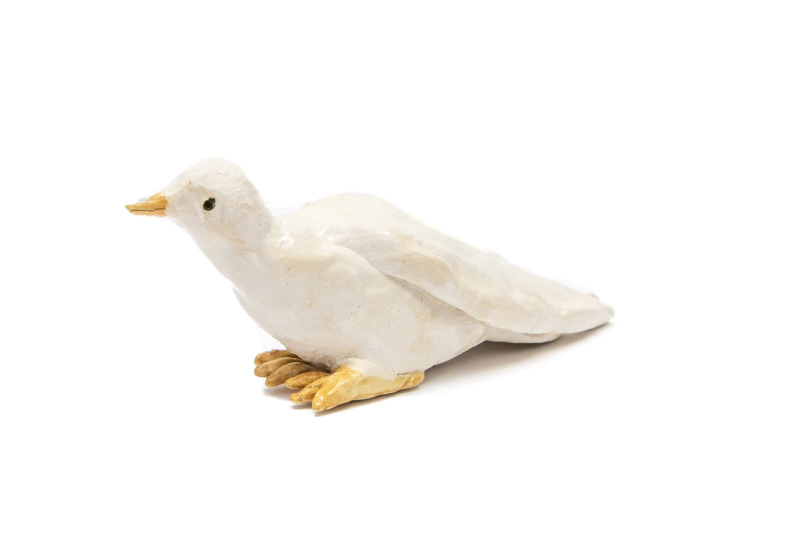 Small ceramic sculpture of a white duck with a golden-yellow beak and feet, viewed in profile against a white background.