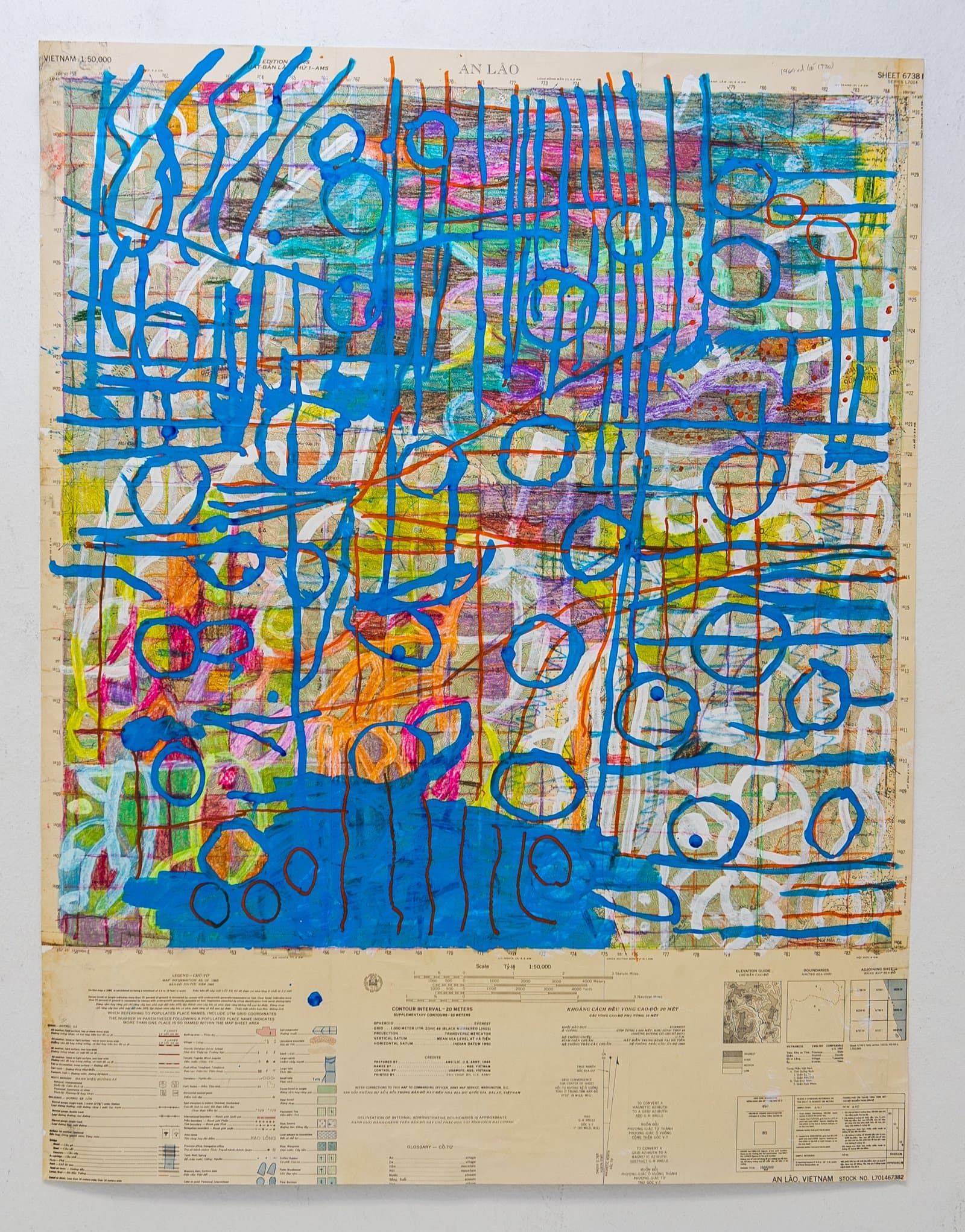 Abstract painting in acrylic on a vintage Vietnam topographic map with bold blue gestural lines, loops, and multicolor underlayers.