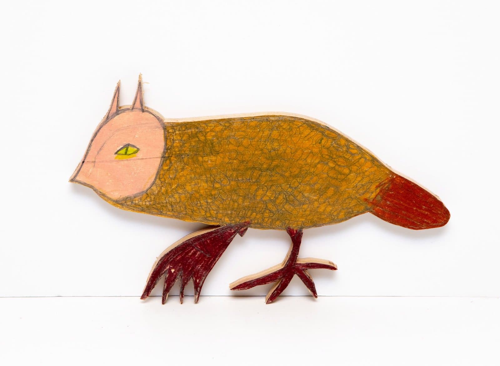 Wooden bird sculpture with peach-colored head, golden textured body, and red tail and feet, drawn with Prismastix.
