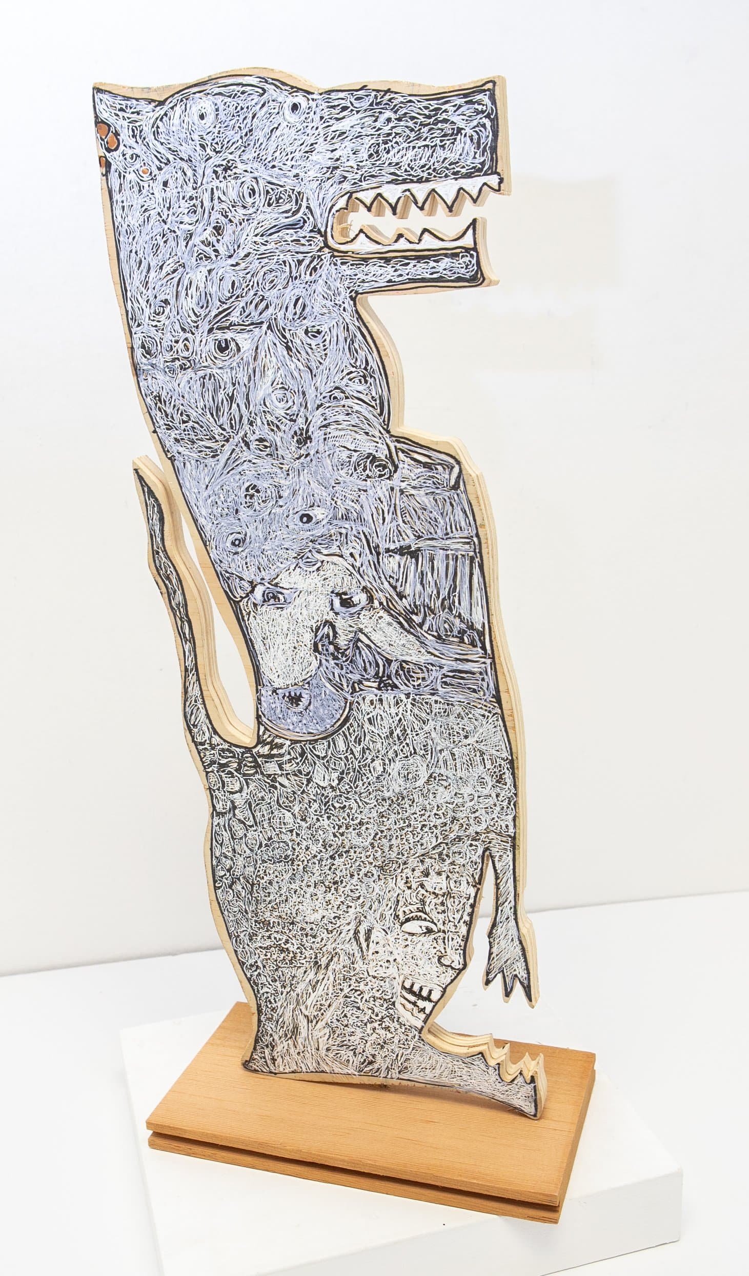 Freestanding cut wood sculpture with gel pen and ink depicting stacked animal figures in swirling blue, white, and black.