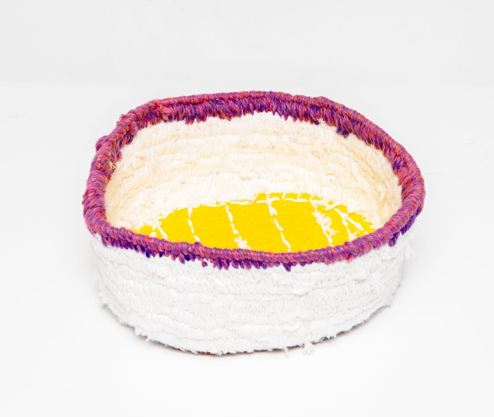 Handwoven coiled basket in white textile with a magenta and purple rim and a bright yellow fabric base interior.