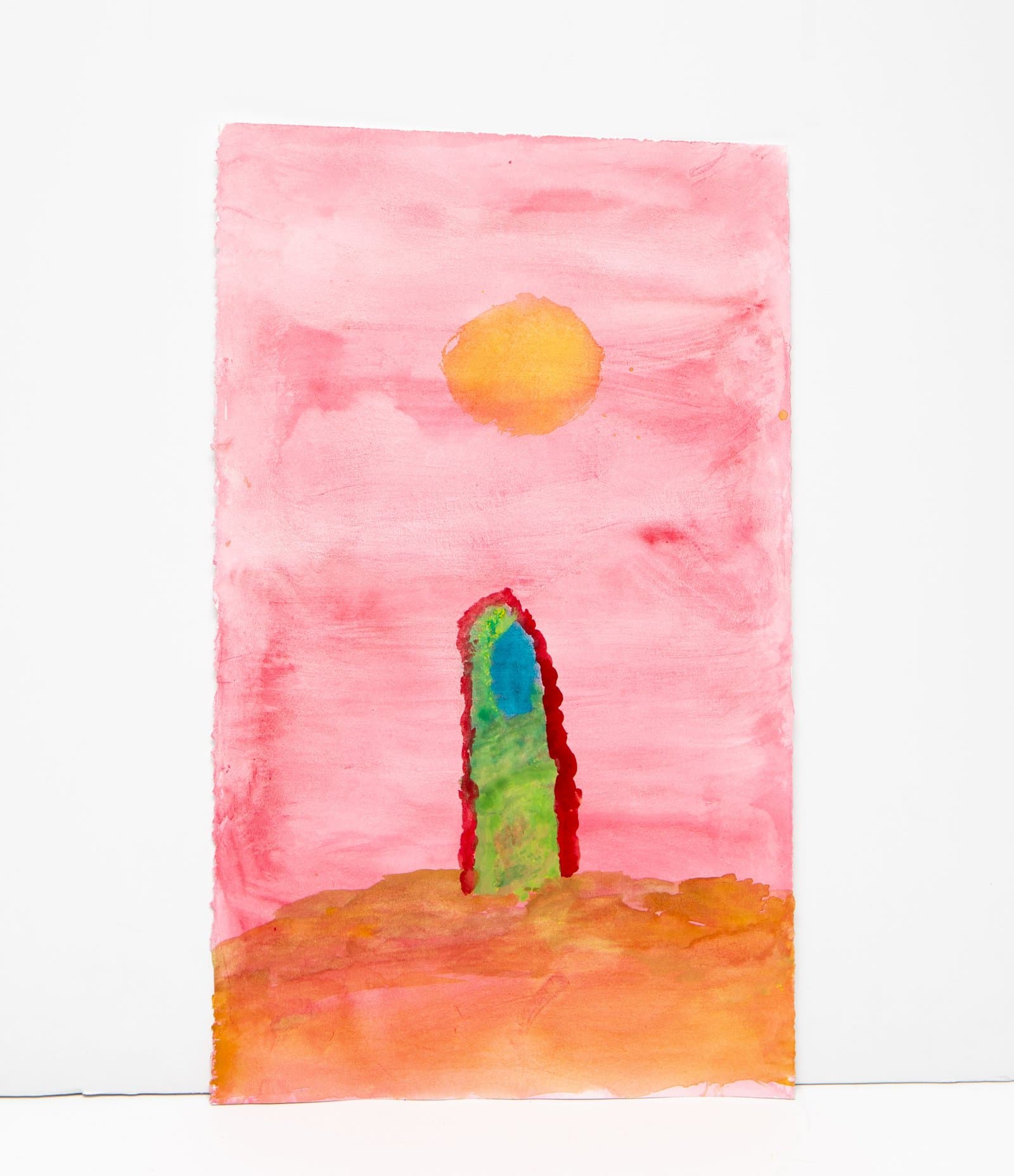 Watercolor painting of a tall green and red tower or cactus form beneath an orange sun in a pink sky above an orange ground.