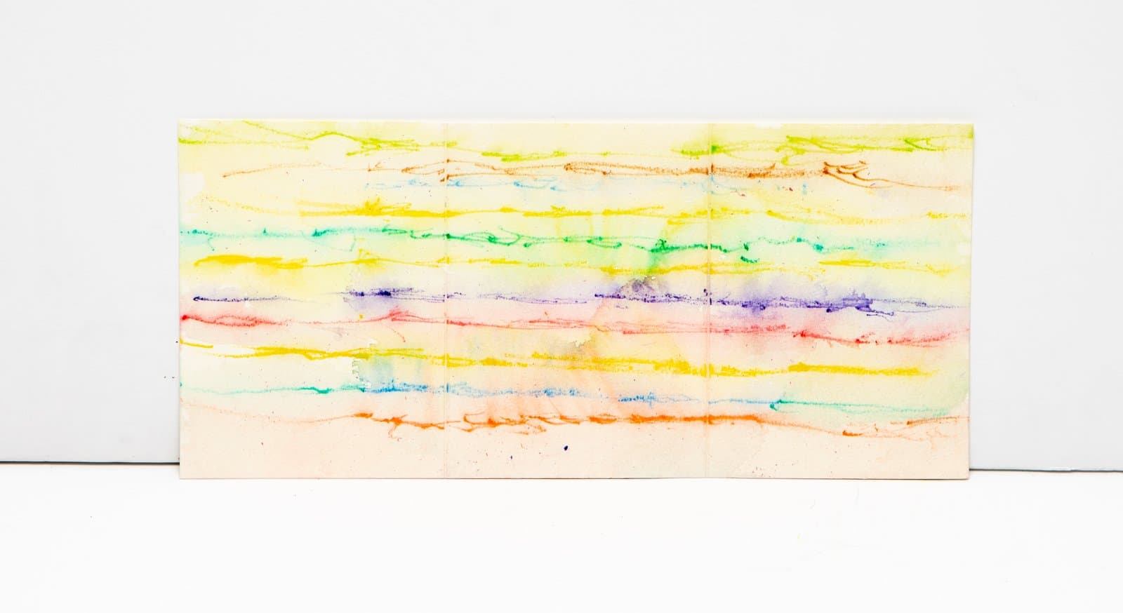 Abstract watercolor on paper with horizontal bands of rainbow colors—yellow, green, teal, purple, red, and orange—on cream ground.