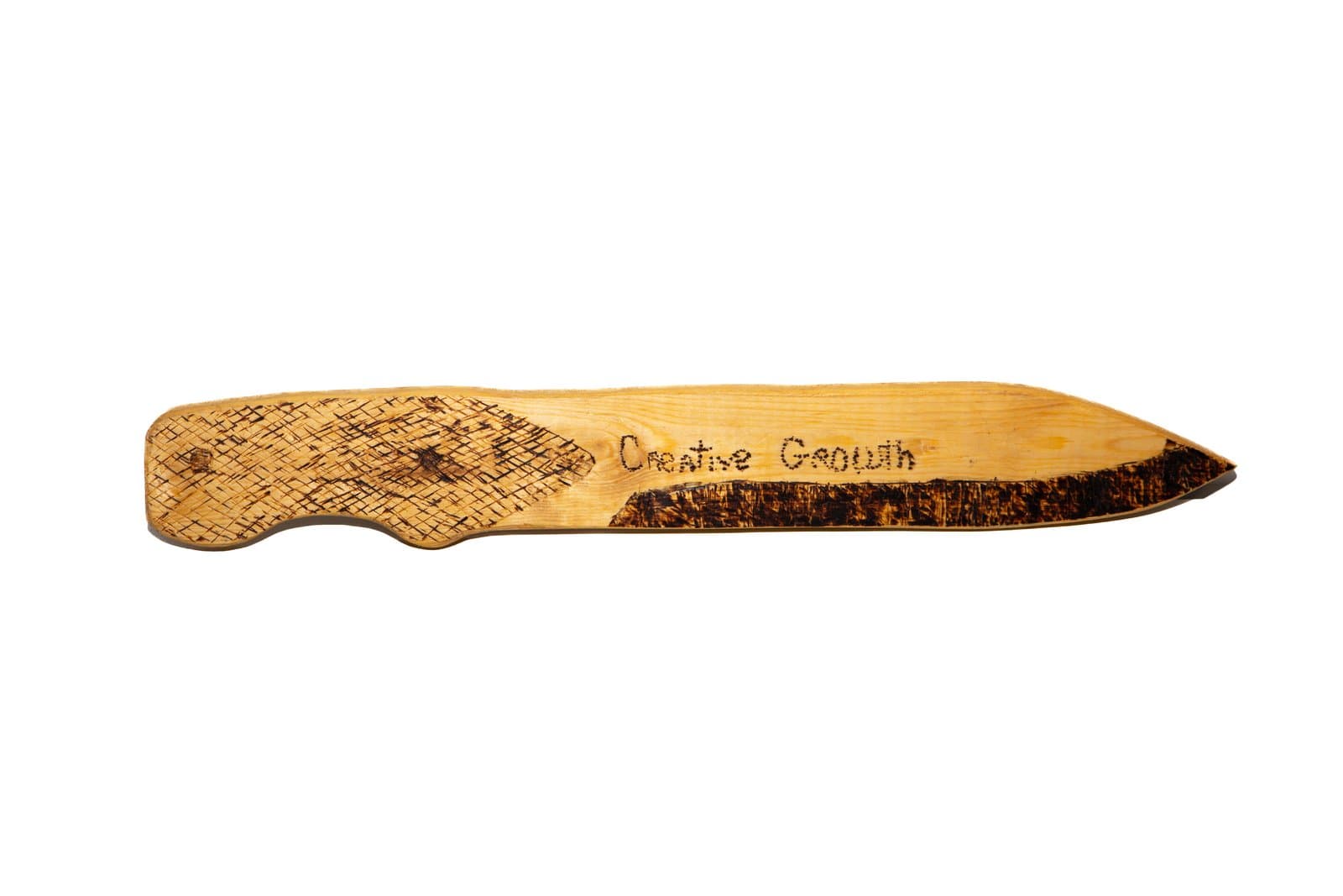 Wooden knife-shaped sculpture with pyrography, featuring a crosshatch pattern and the text 'Creative Growth' burned into the surface.