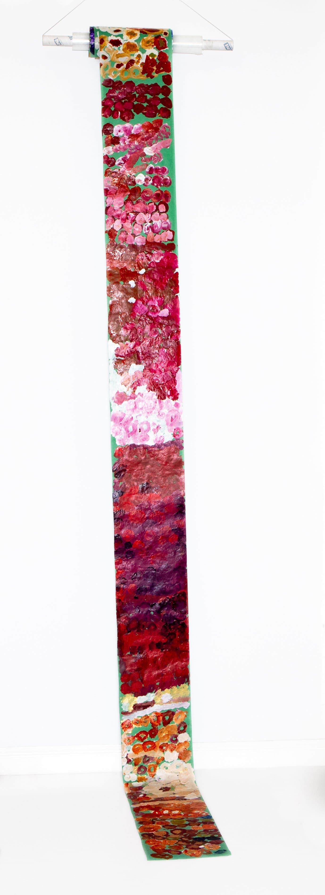 Tall narrow vertical scroll painting in acrylic with dense circular marks in pinks, reds, and purples on green paper.