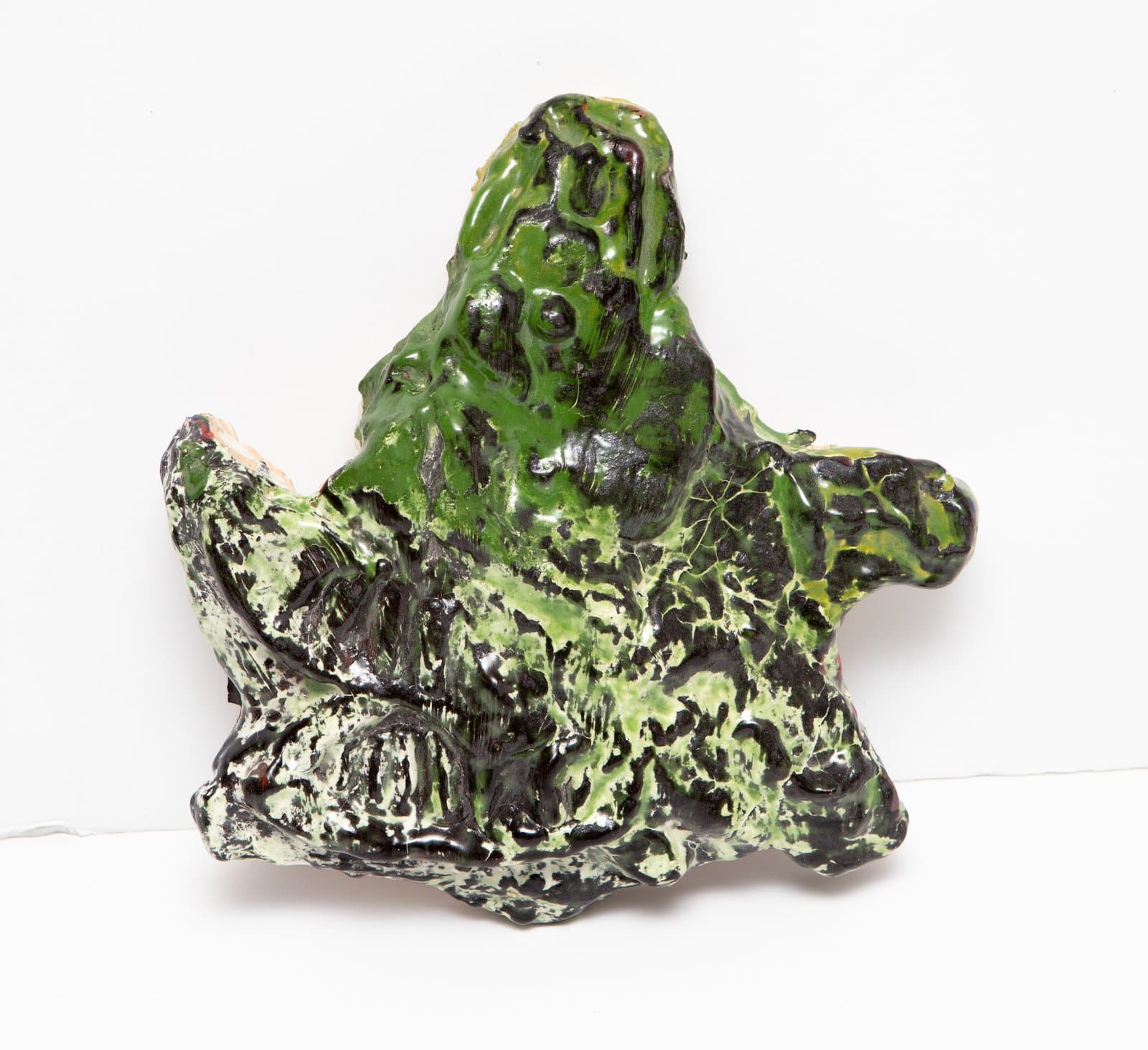 Ceramic sculpture with irregular, roughly star-shaped form covered in glossy green and black mottled glaze.