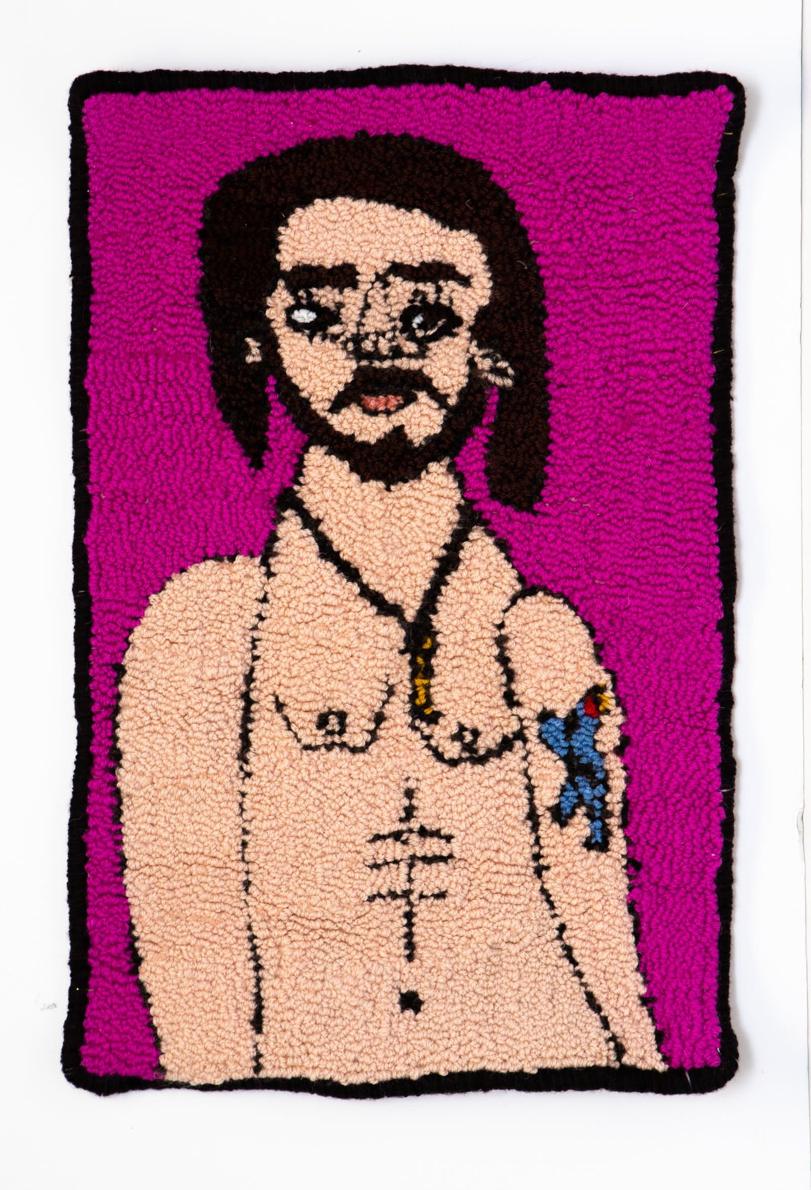Hooked rug portrait of a bearded man with dark hair against a vivid magenta background, featuring a cross tattoo and arm tattoo.