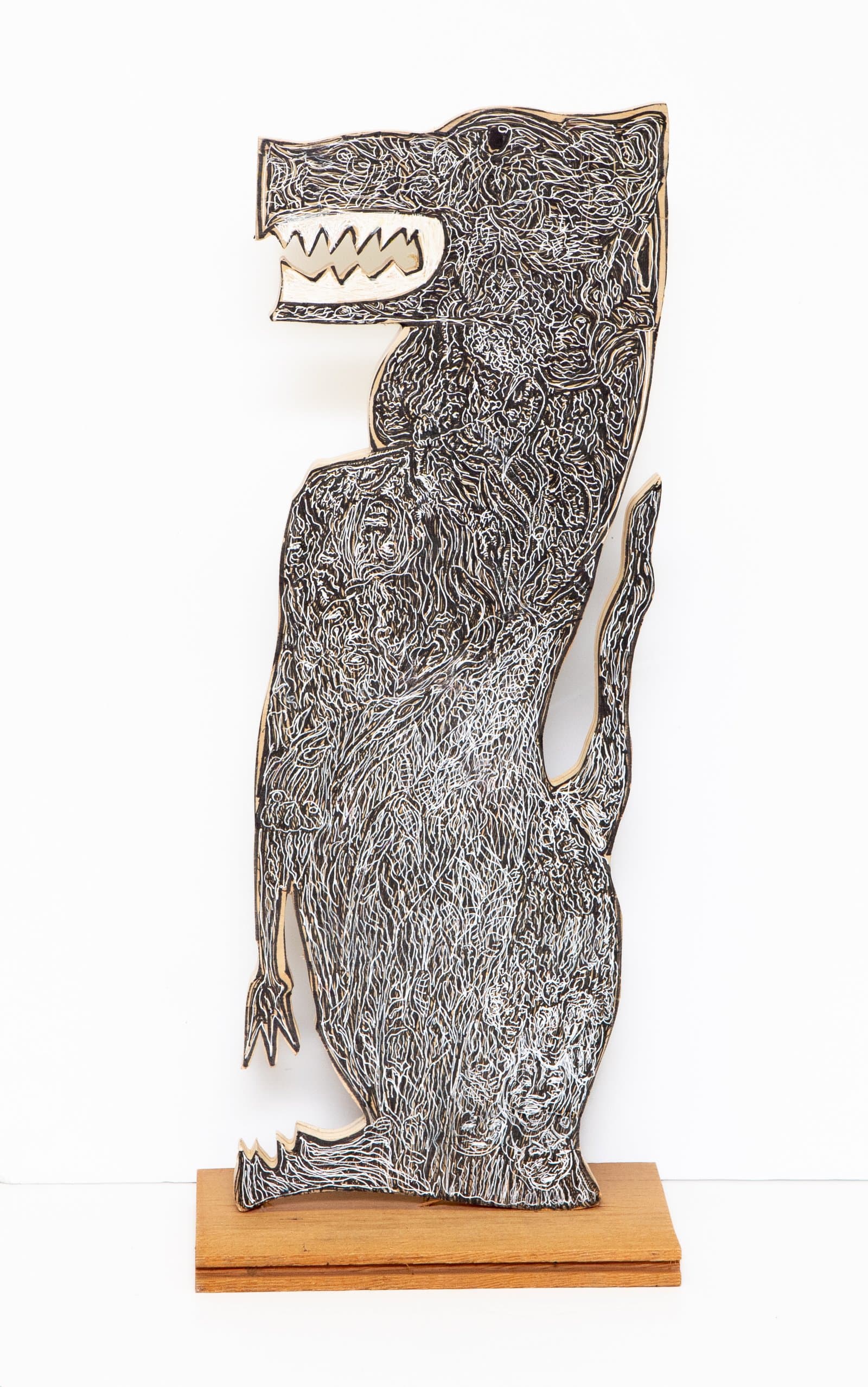 Cut wood sculpture of a standing dog figure covered in dense black and white swirling lines, mounted on a wood base.