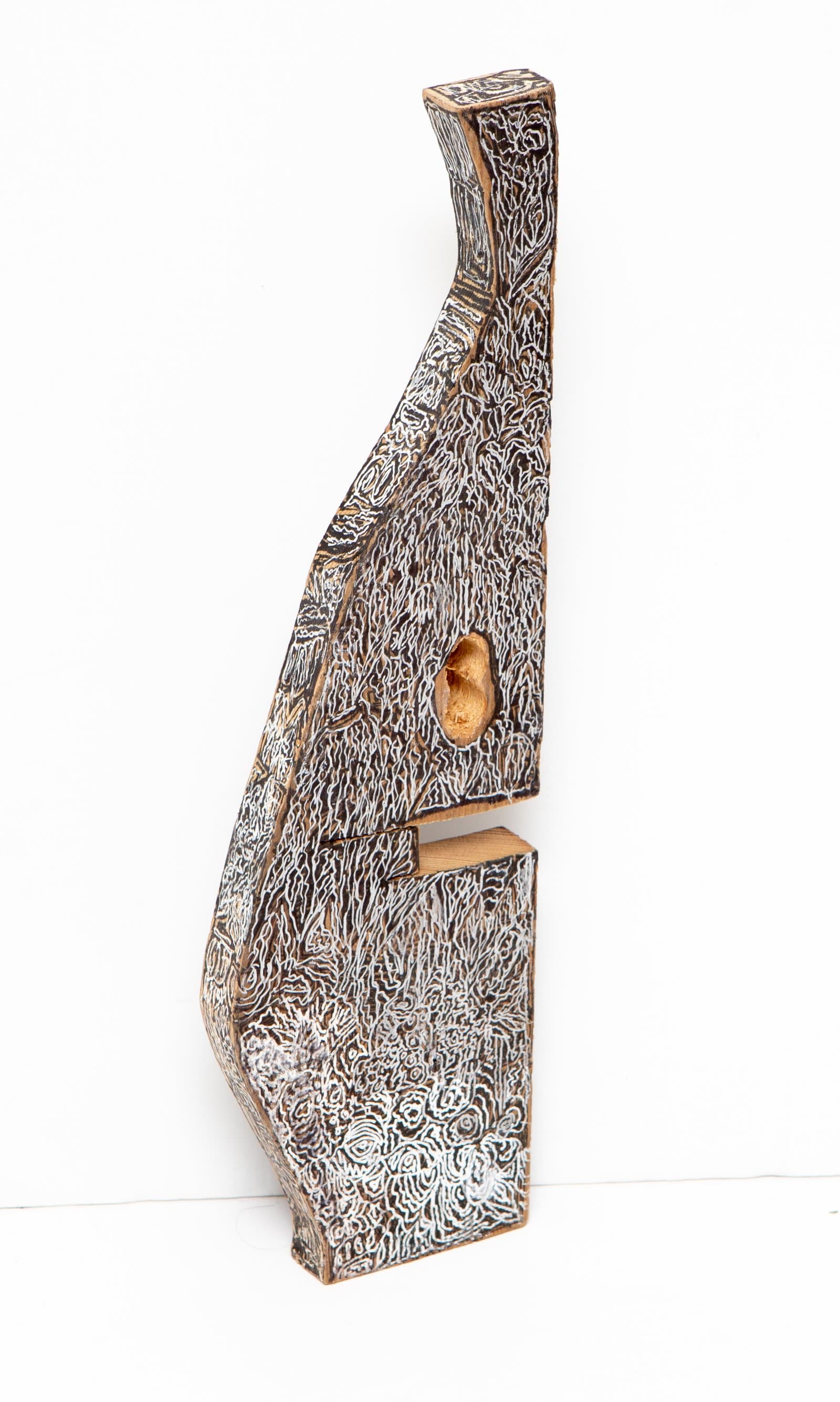 Tall abstract wood sculpture covered in dense white line patterns on dark ground, with a natural knot hole opening near center.