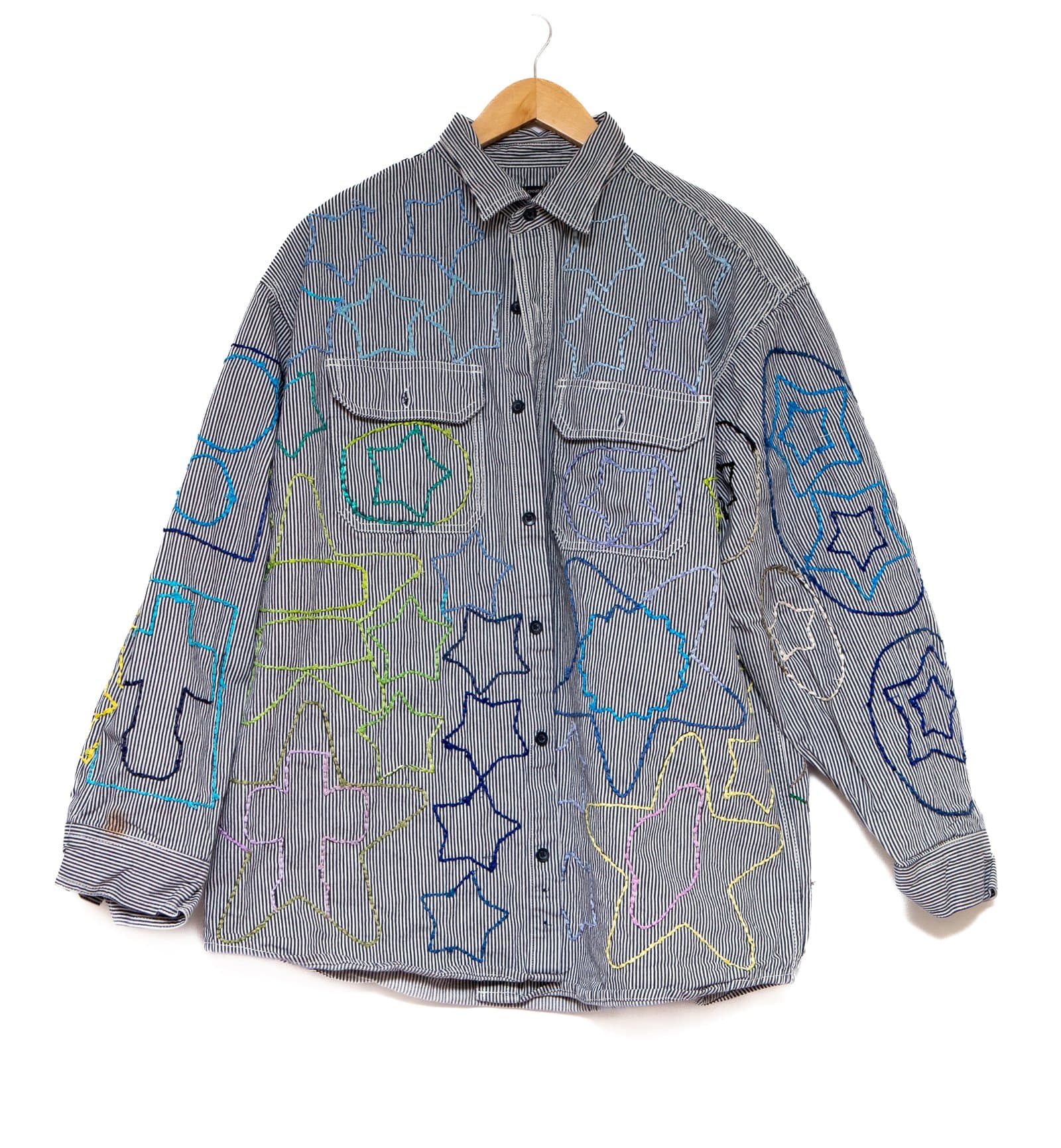 Embroidered blue-and-white striped button-up shirt on a wooden hanger with multicolored thread designs across the fabric.