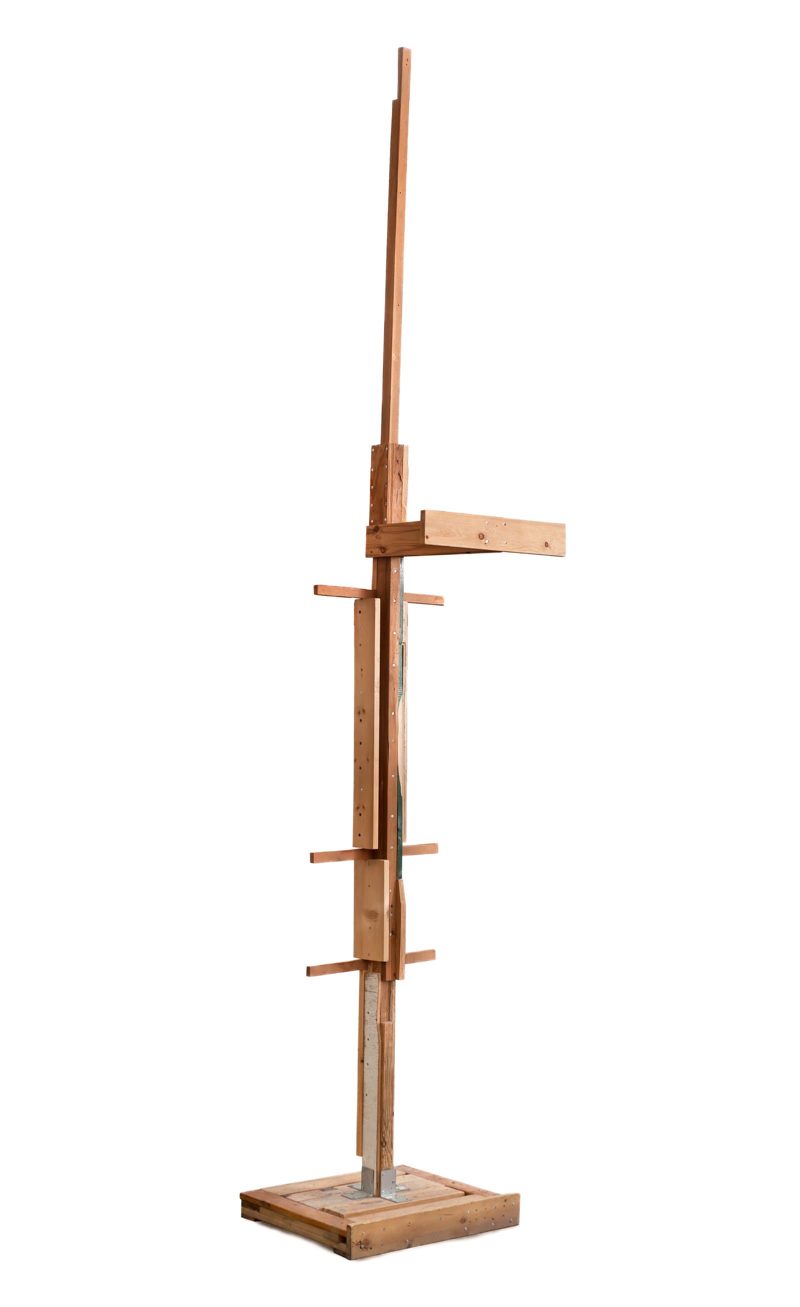 Tall freestanding wood sculpture with a vertical central post, asymmetric horizontal crossbars, and a square base.