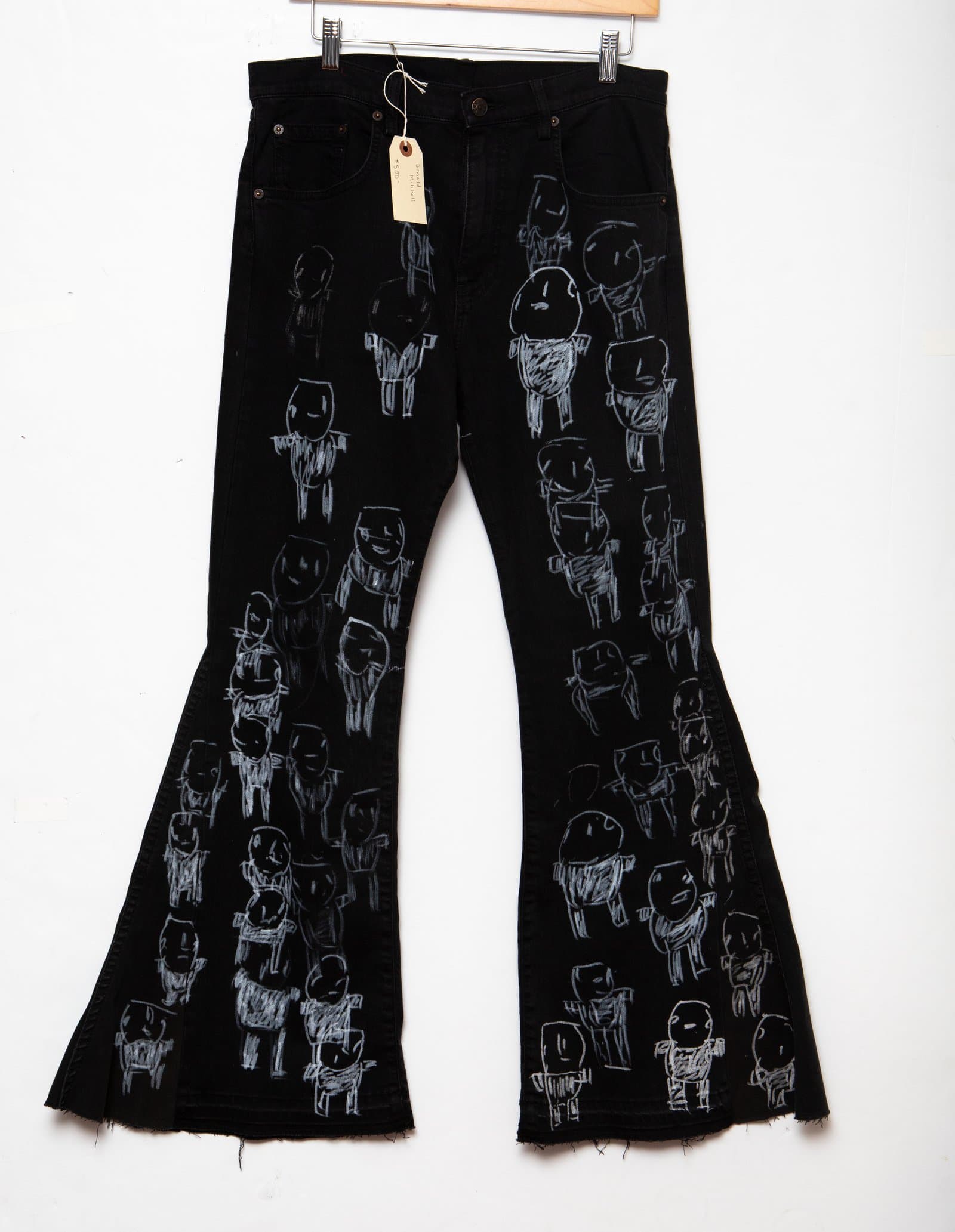 Black flare-leg denim jeans hand-painted with rows of small schematic human figures in white and gray paint.