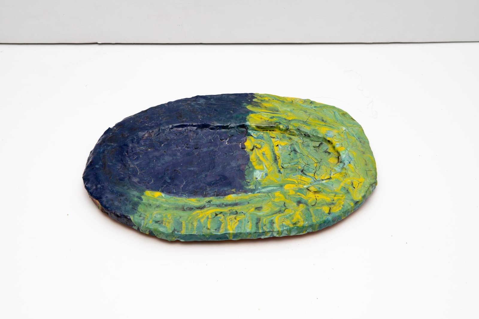 Oval ceramic dish painted in navy blue and yellow-green with thick, textured brushwork on a white surface.