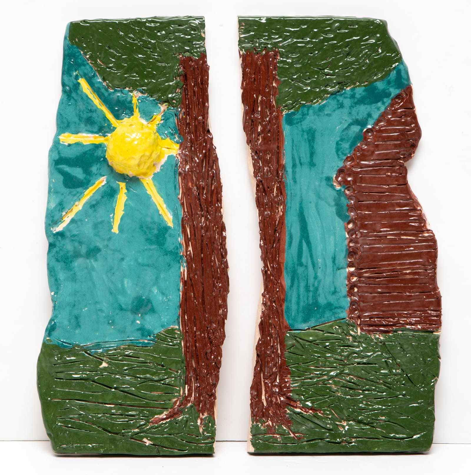 Two glazed ceramic relief panels depicting a landscape with trees, green grass, teal sky, and a yellow sun.
