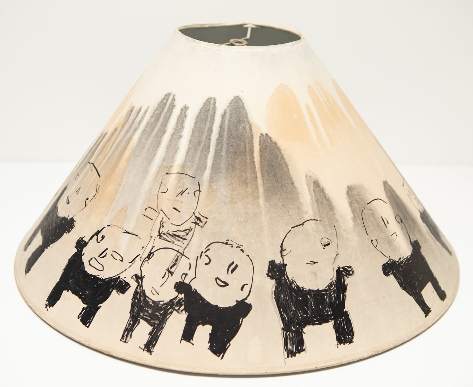 Conical lamp shade painted with black ink figures of rounded human heads atop four-legged animal bodies on cream ground.