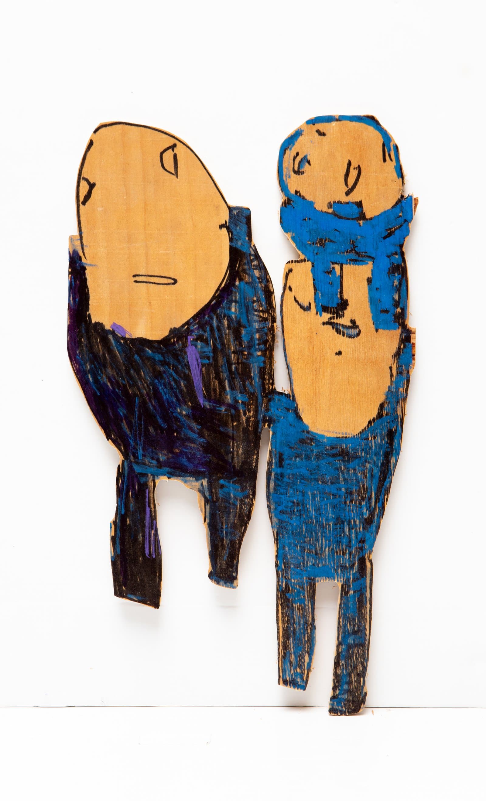 Two cut-out wood figures painted with acrylic marker, one in black and purple, one in blue, both with tan oval faces.