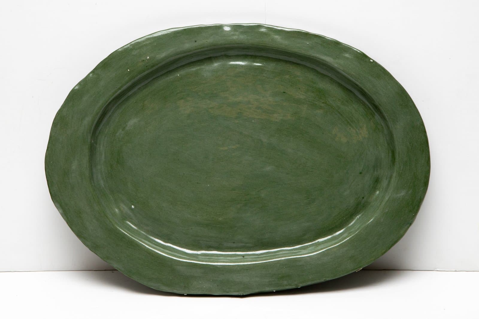 Large oval ceramic platter with a wide rim, glazed in matte and slightly glossy green tones.