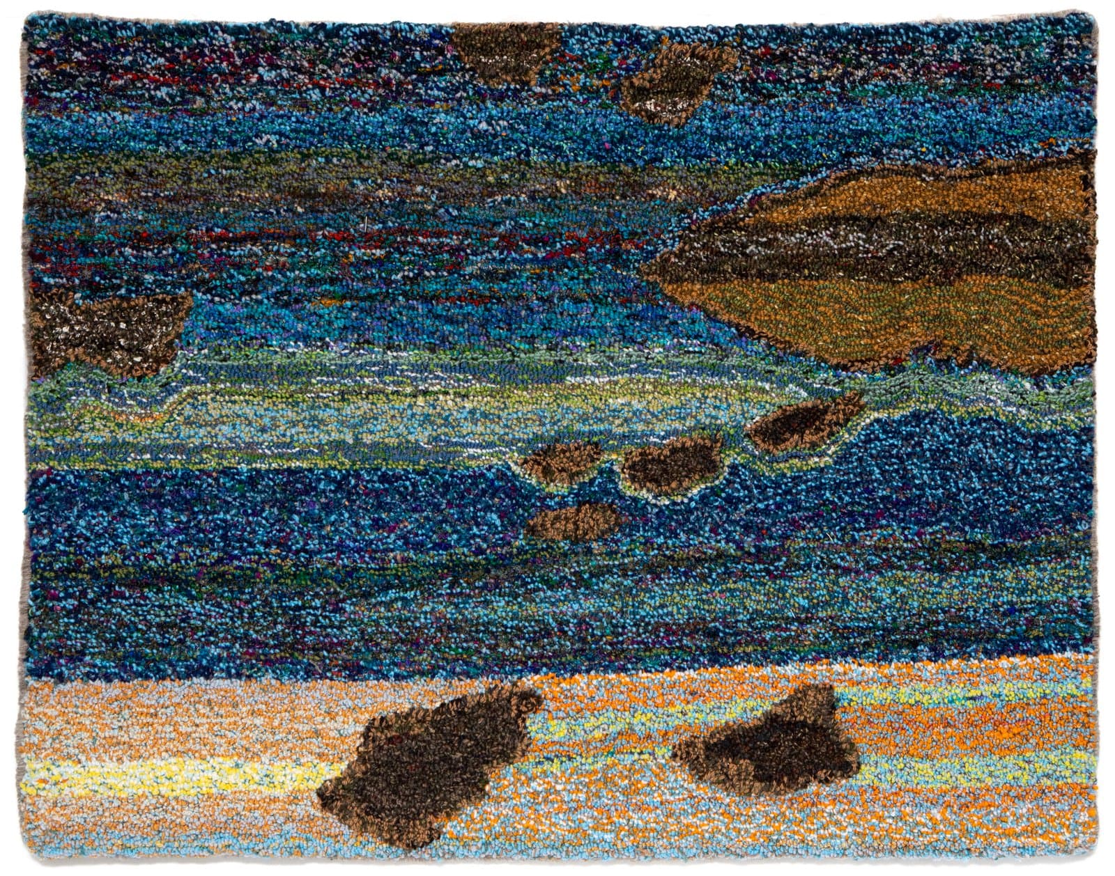 Hooked rug depicting a coastal landscape with blue water, rocky shoreline, and sandy beach in multi-colored yarn.