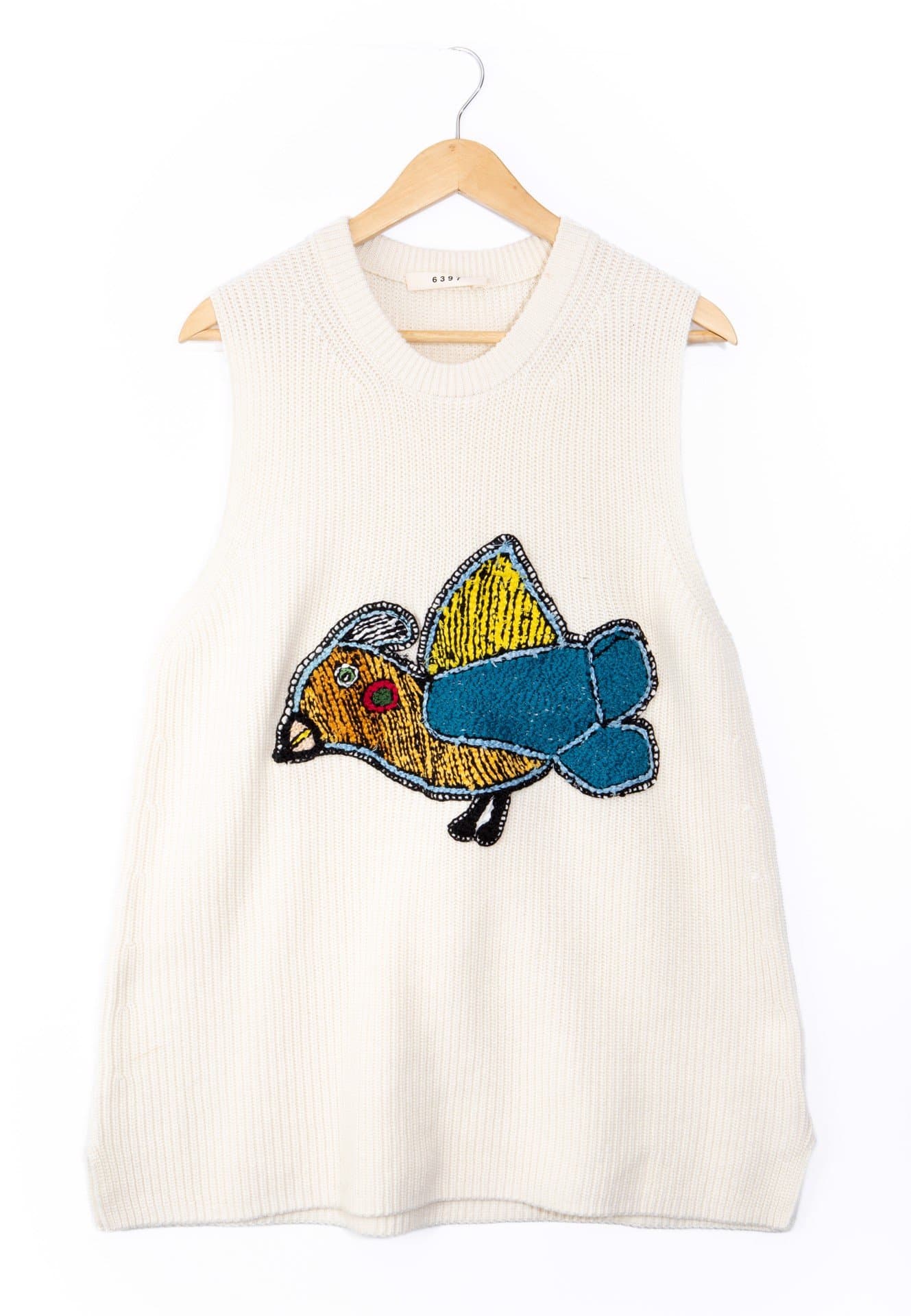 Sleeveless white knit vest with embroidered fish motif in yellow, orange, and blue on wooden hanger.