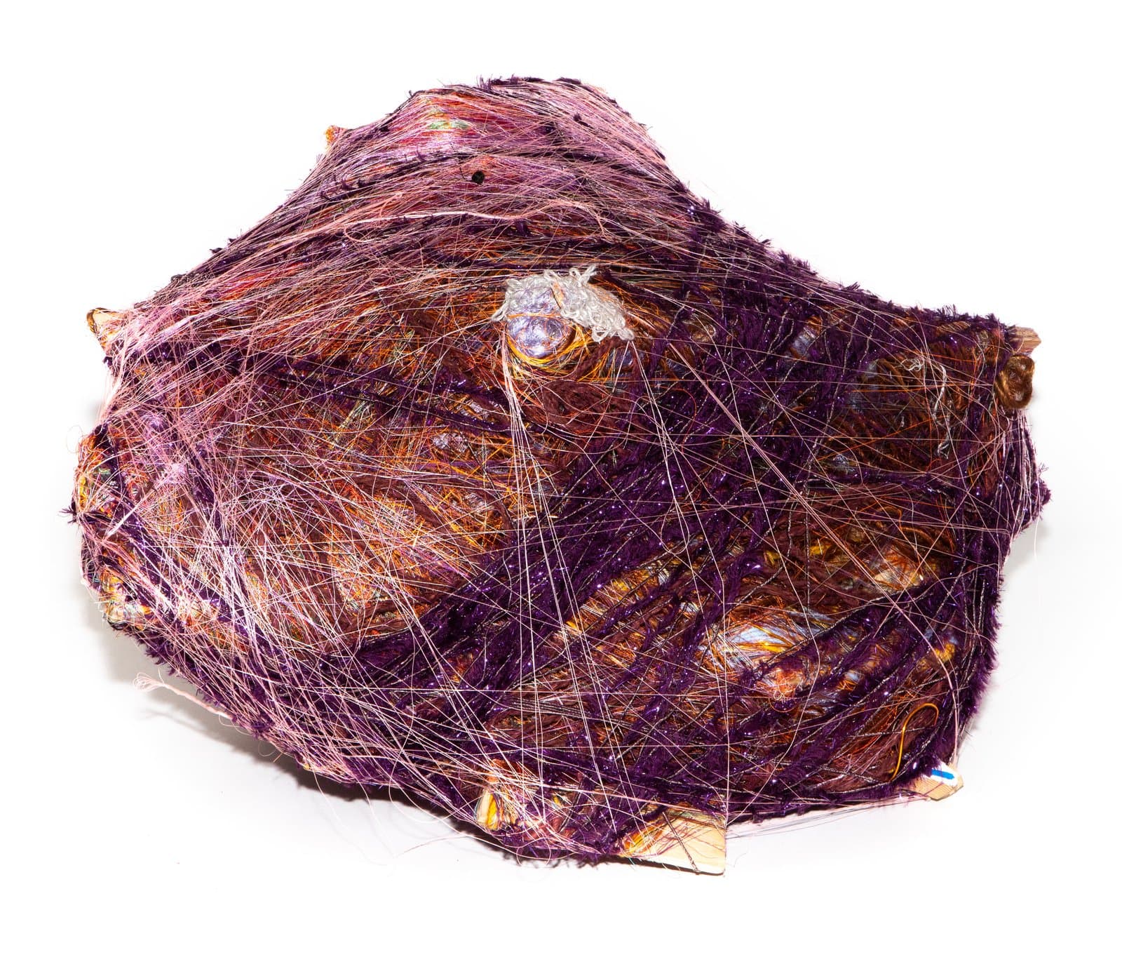 Mounded wrapped sculpture densely layered with purple, orange, and pink fibers and threads on a white background.