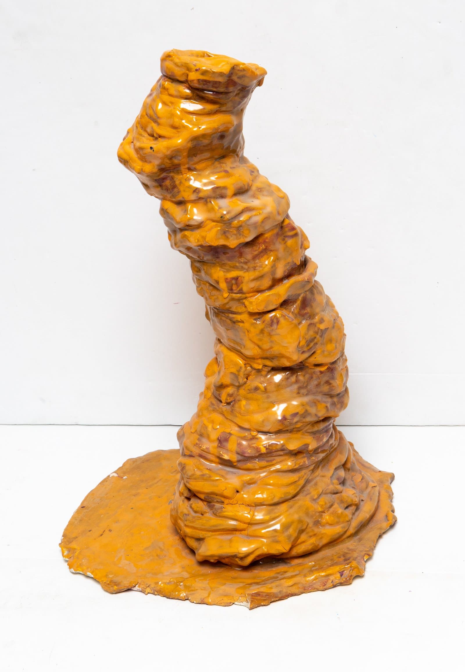 Ceramic sculpture: a tall, tapering spiral column in amber-orange glaze, rising from a flat irregular base.