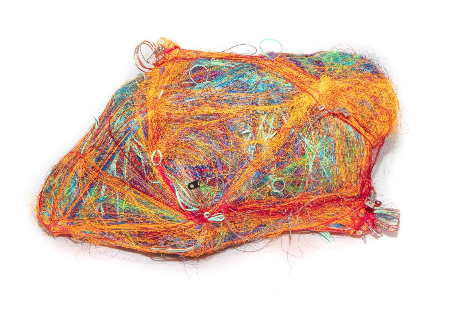 Wrap sculpture of densely tangled orange, red, green, and blue fibers with embedded metal rings on white background.