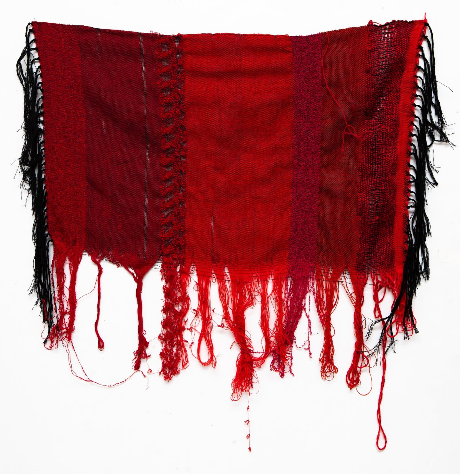 Woven textile artwork in deep red and black with unraveling fringe along the bottom and sides.