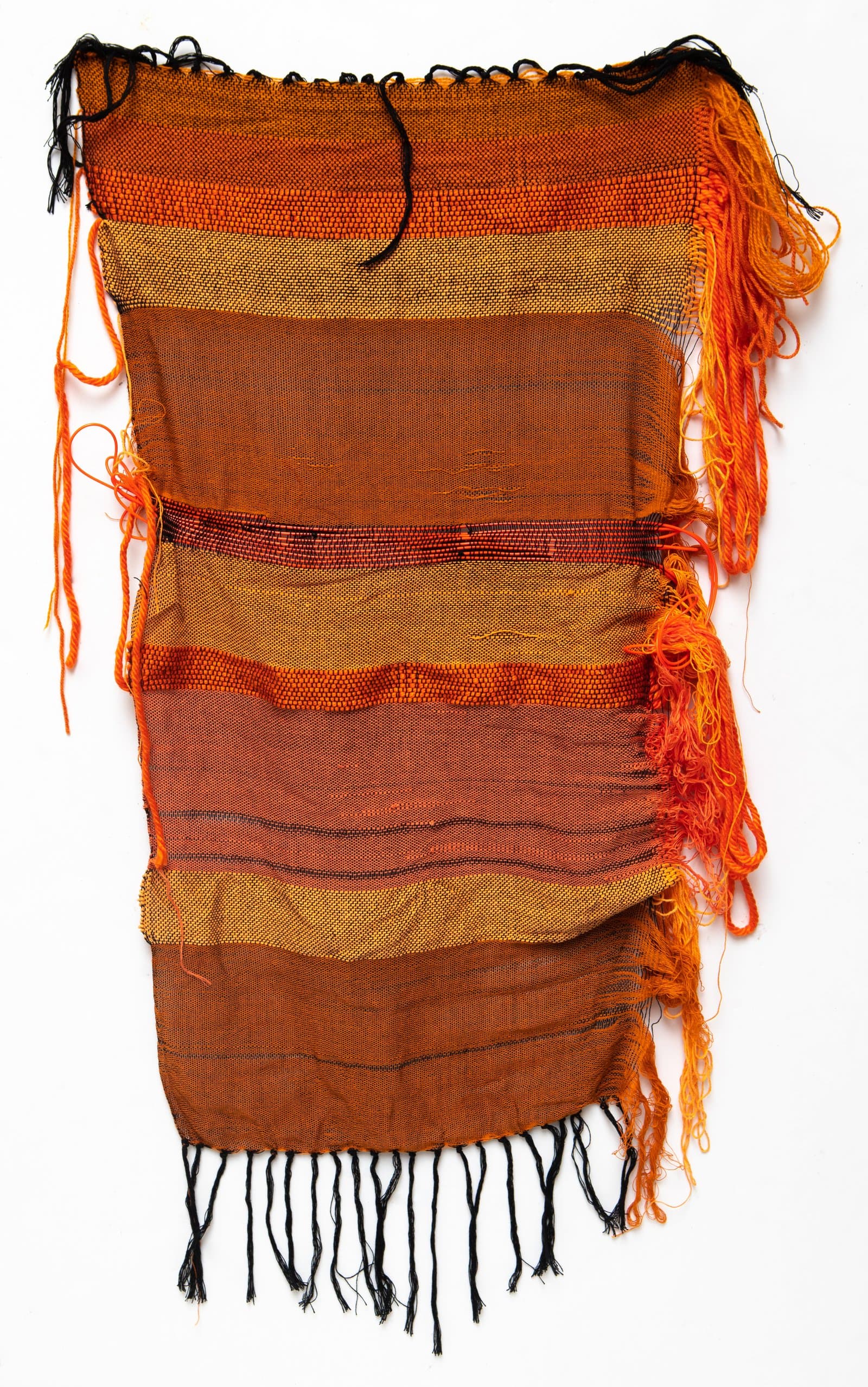 Woven textile in warm oranges, golds, and browns with horizontal stripe bands and fringe along edges.