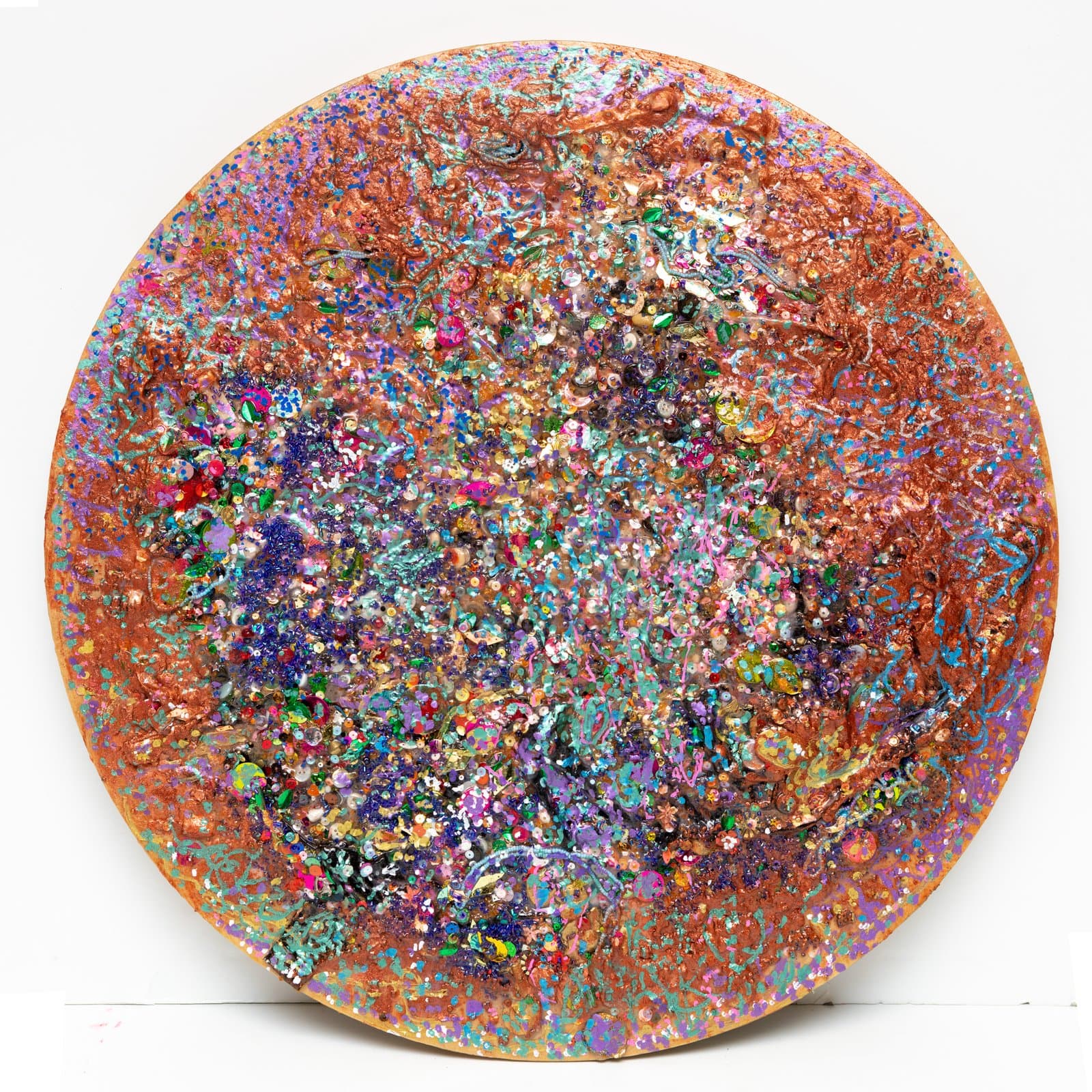 Circular mixed media artwork on wood panel densely covered in glitter, sequins, and paint in copper, pink, blue, and multicolor.