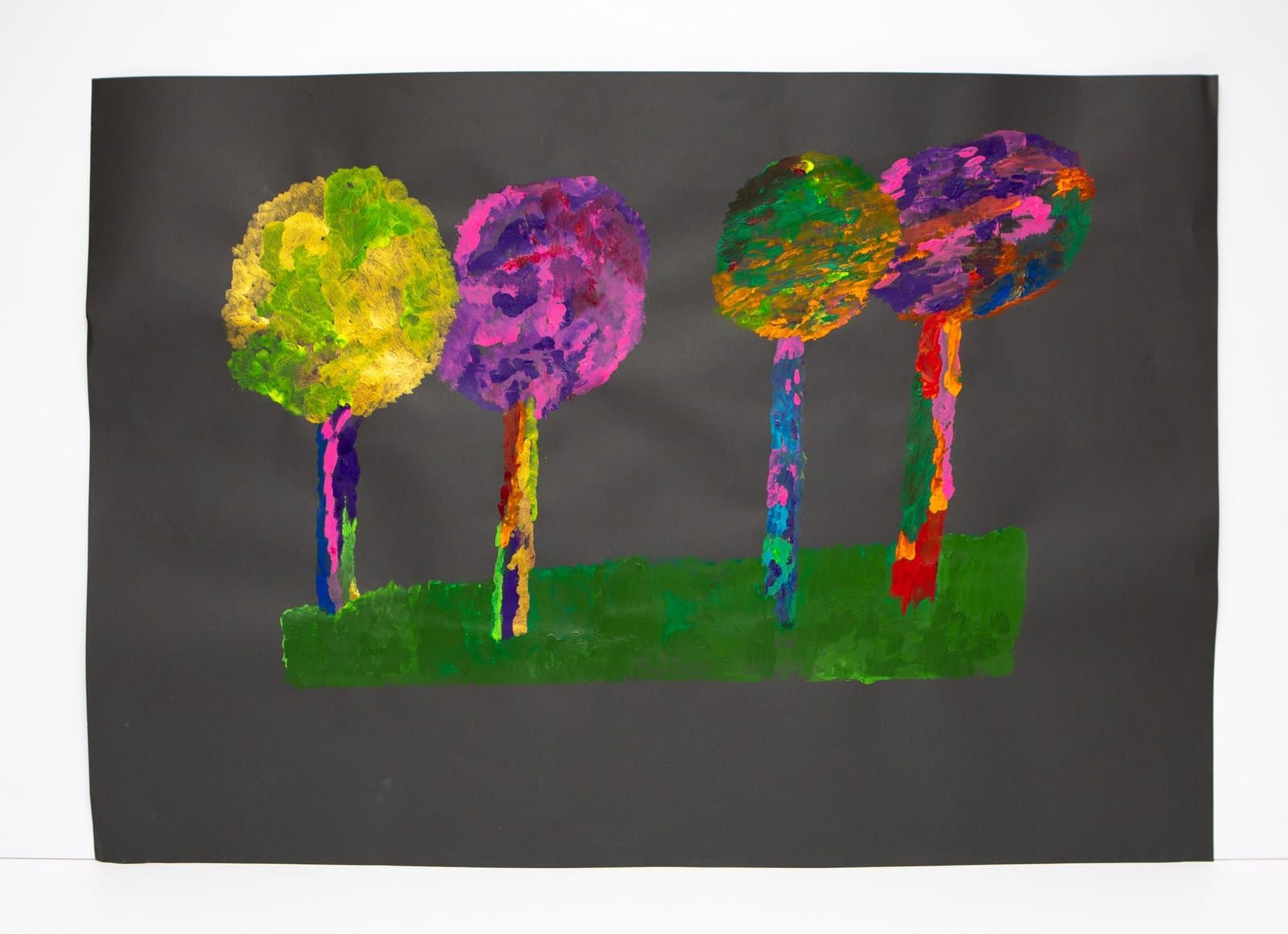 Painting of four colorful trees with circular crowns on multicolored trunks against dark gray sky and green ground.