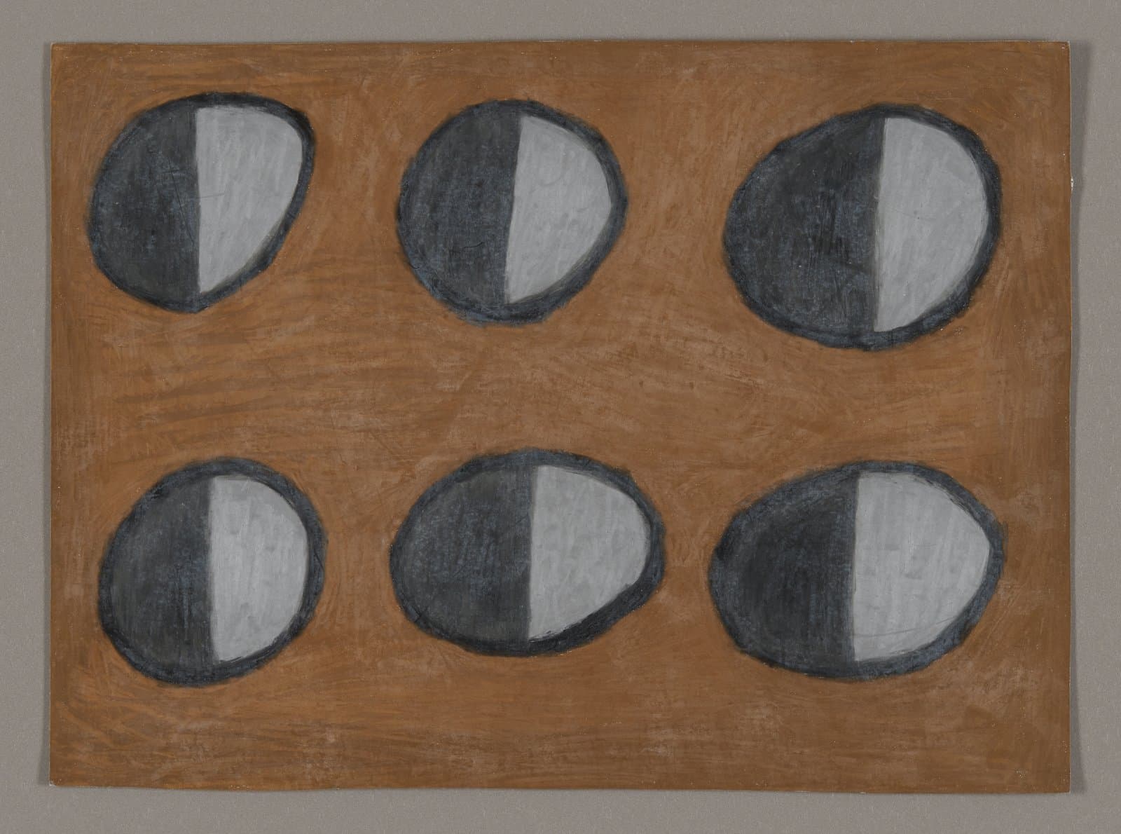 Drawing of six oval shapes arranged in two rows on brown paper, each divided into dark and light halves