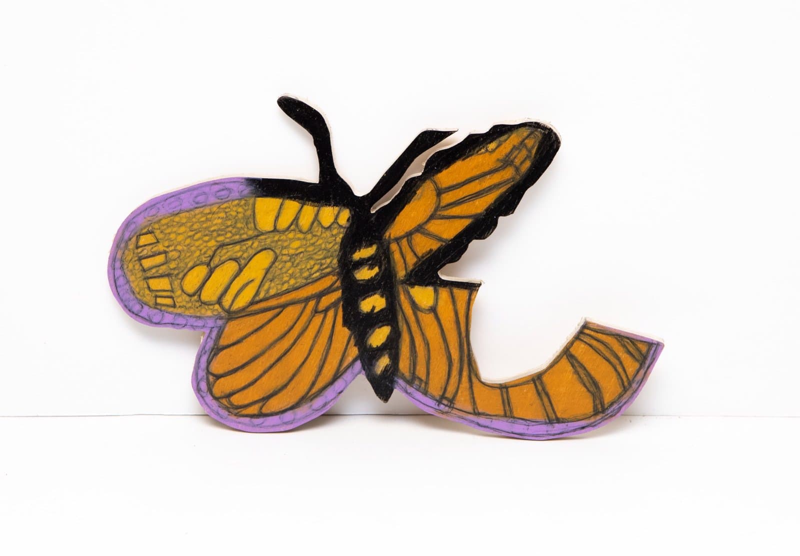 Sculptural butterfly with orange and yellow wings outlined in black, mounted on white background.