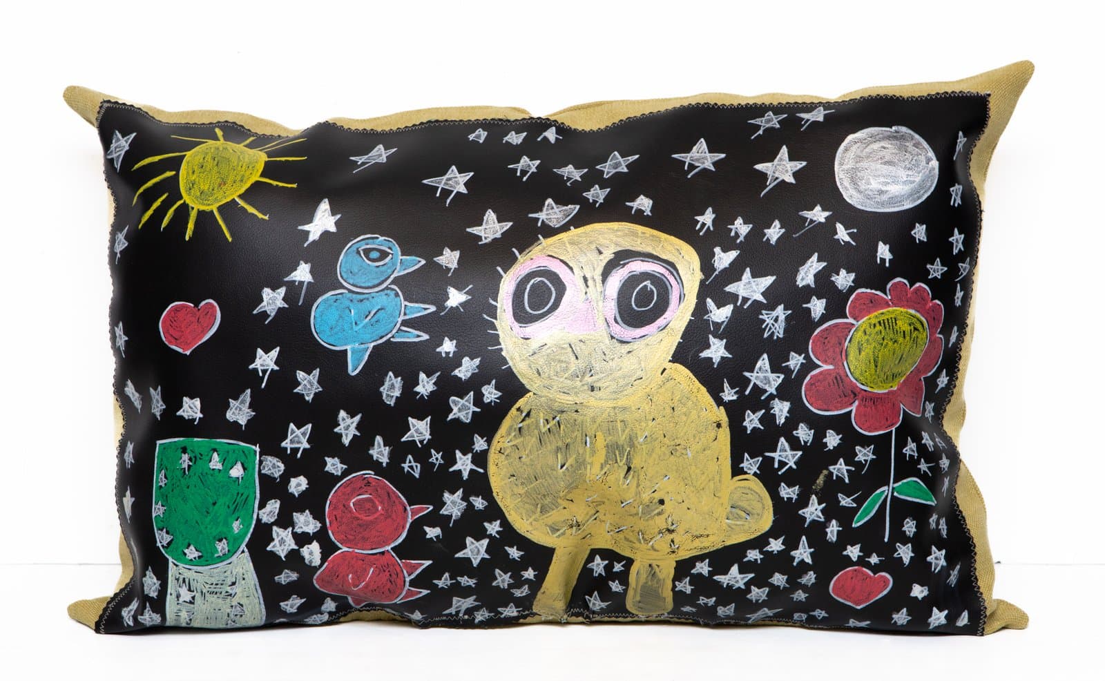 Rectangular pillow with black leather face painted with a yellow owl-like figure, stars, flowers, and small animals.