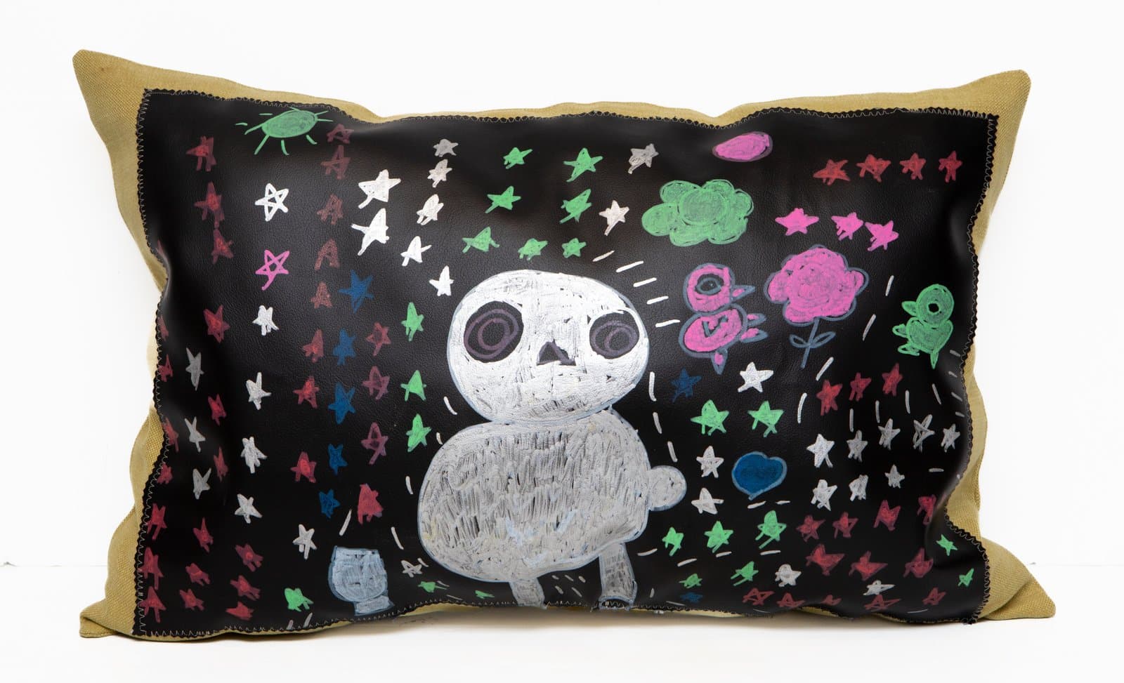 Decorative pillow with acrylic on black leather panel showing a skull figure surrounded by colorful stars and flowers.