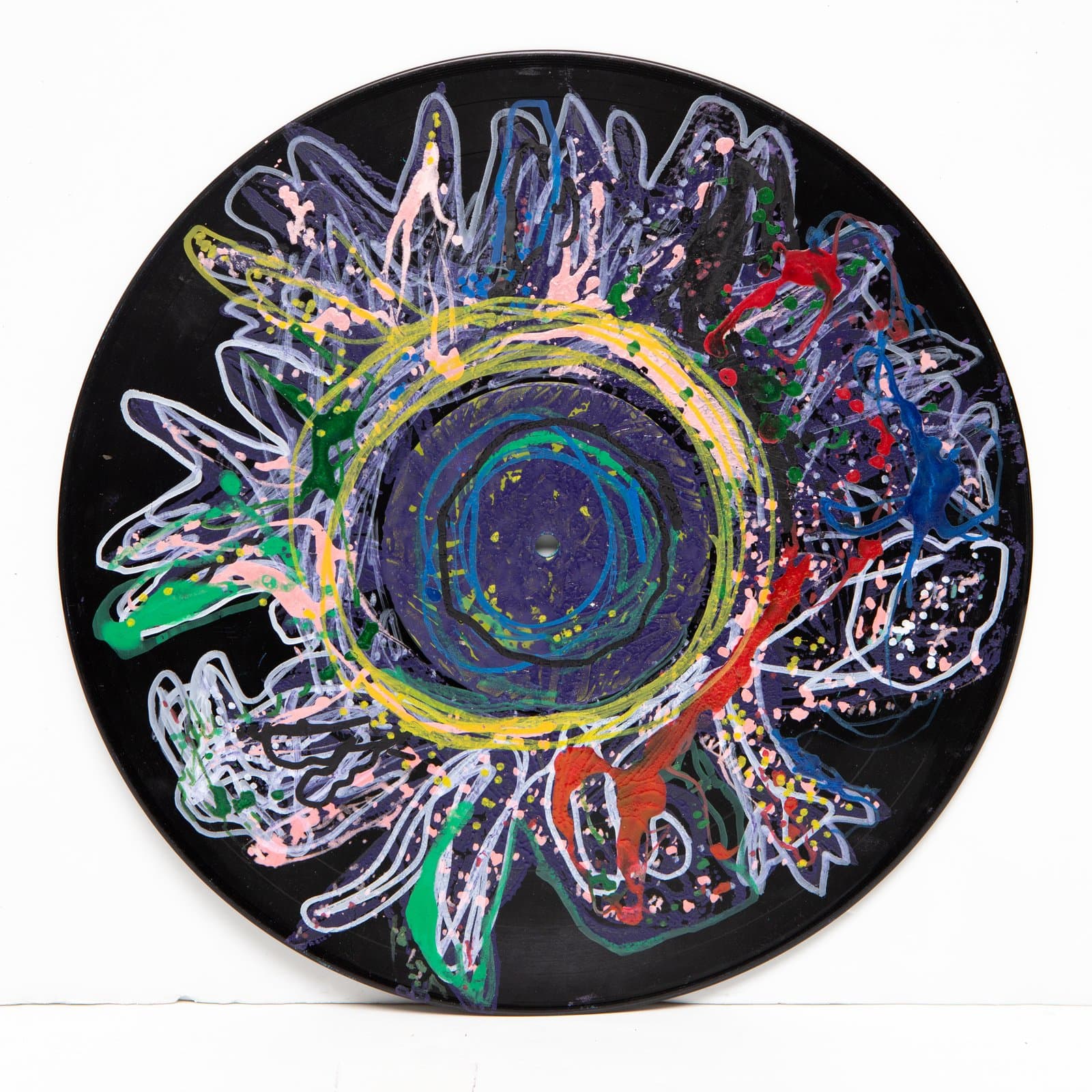 Abstract acrylic painting on a vinyl record with a floral burst design in yellow, green, blue, pink, and red on black.