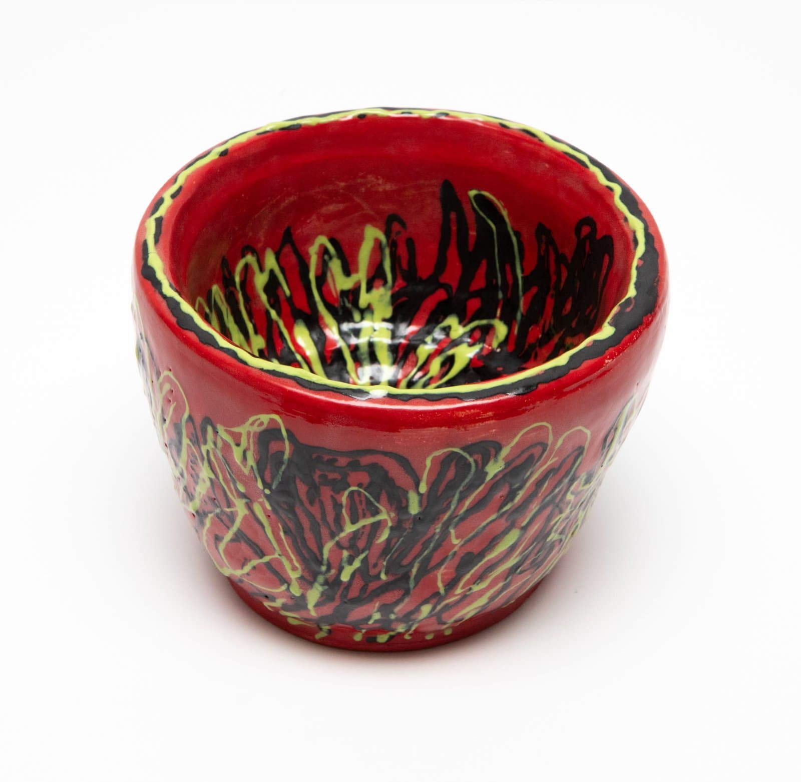 Small red glazed ceramic bowl with energetic black and yellow-green dripped mark-making on exterior and interior.