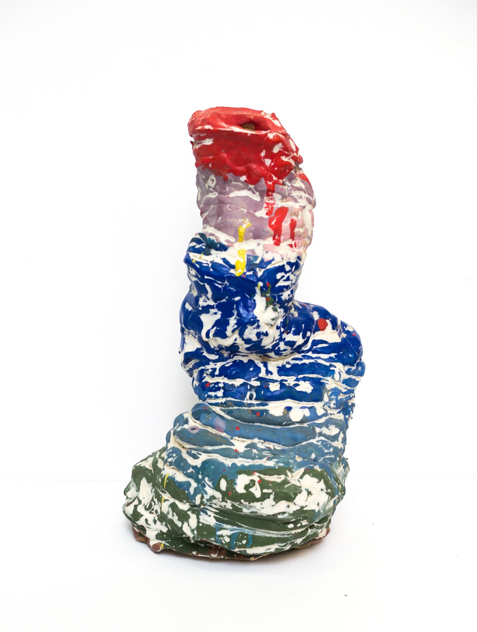 Painted ceramic sculpture with stacked organic forms in red, blue, green, and white on a white background.