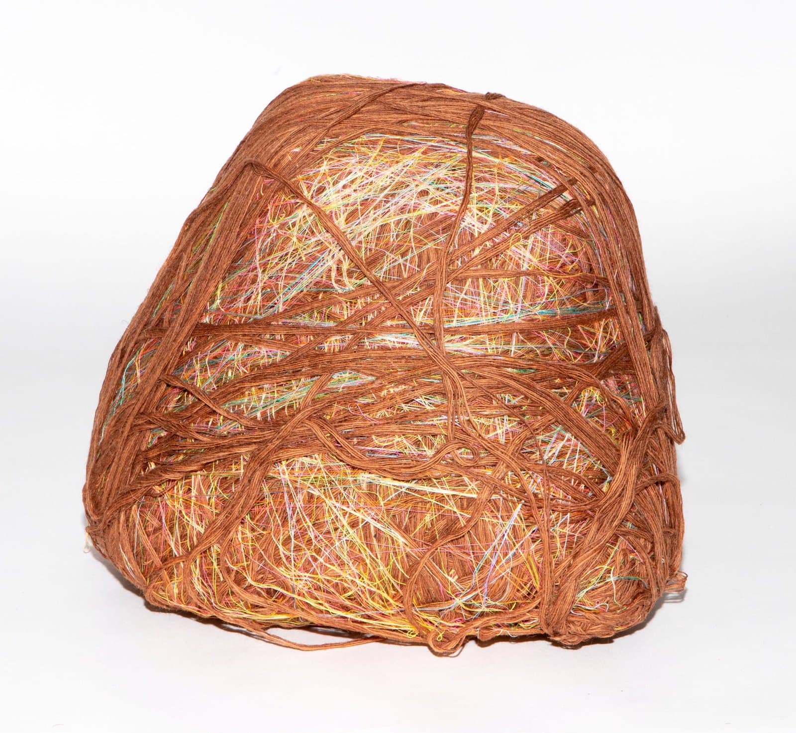Fiber sculpture of densely wrapped brown cord with multicolored threads woven throughout, forming a rounded bundle.
