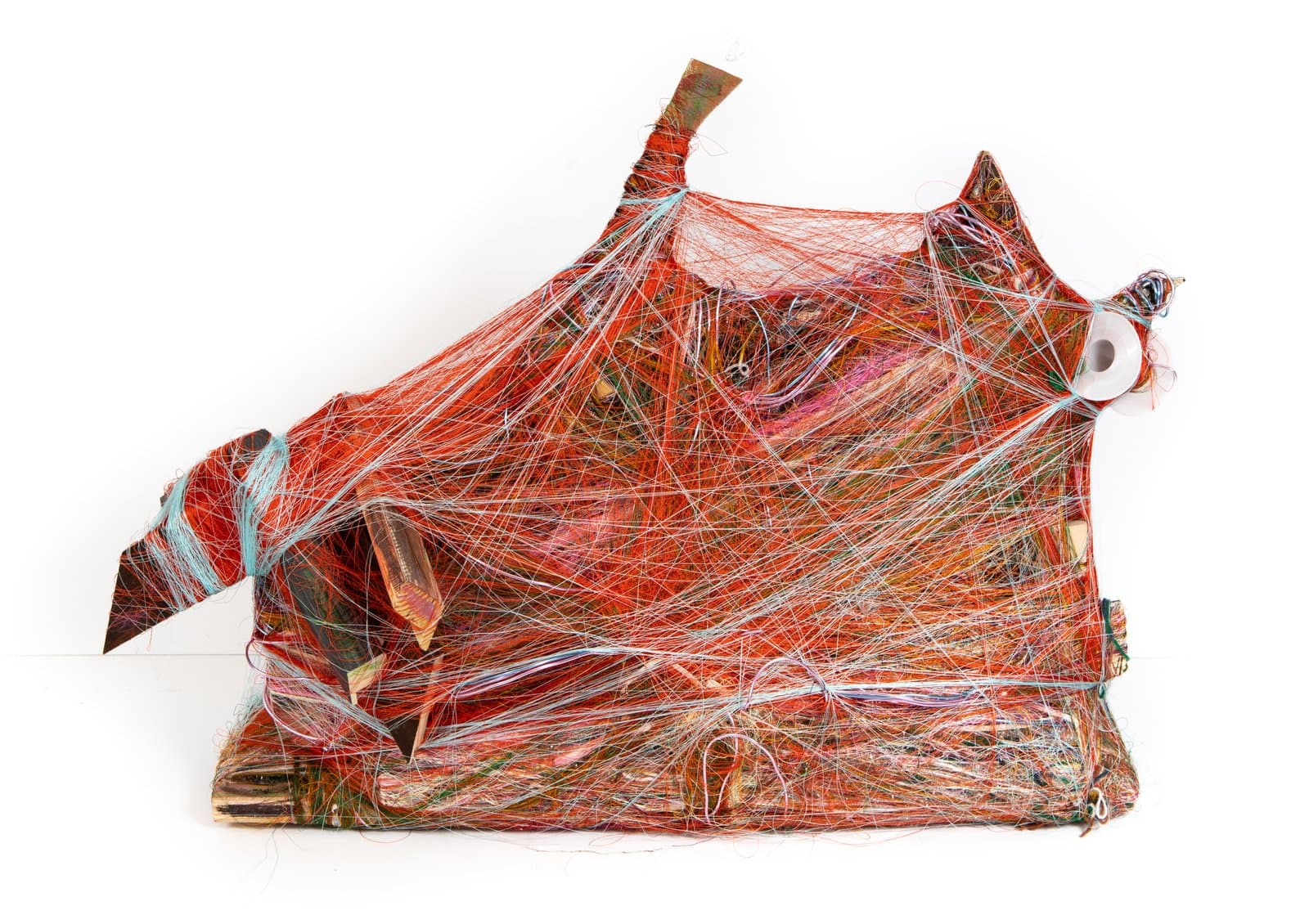 Mixed-media sculpture densely wrapped in multicolored thread and yarn, predominantly red-orange, with embedded objects.