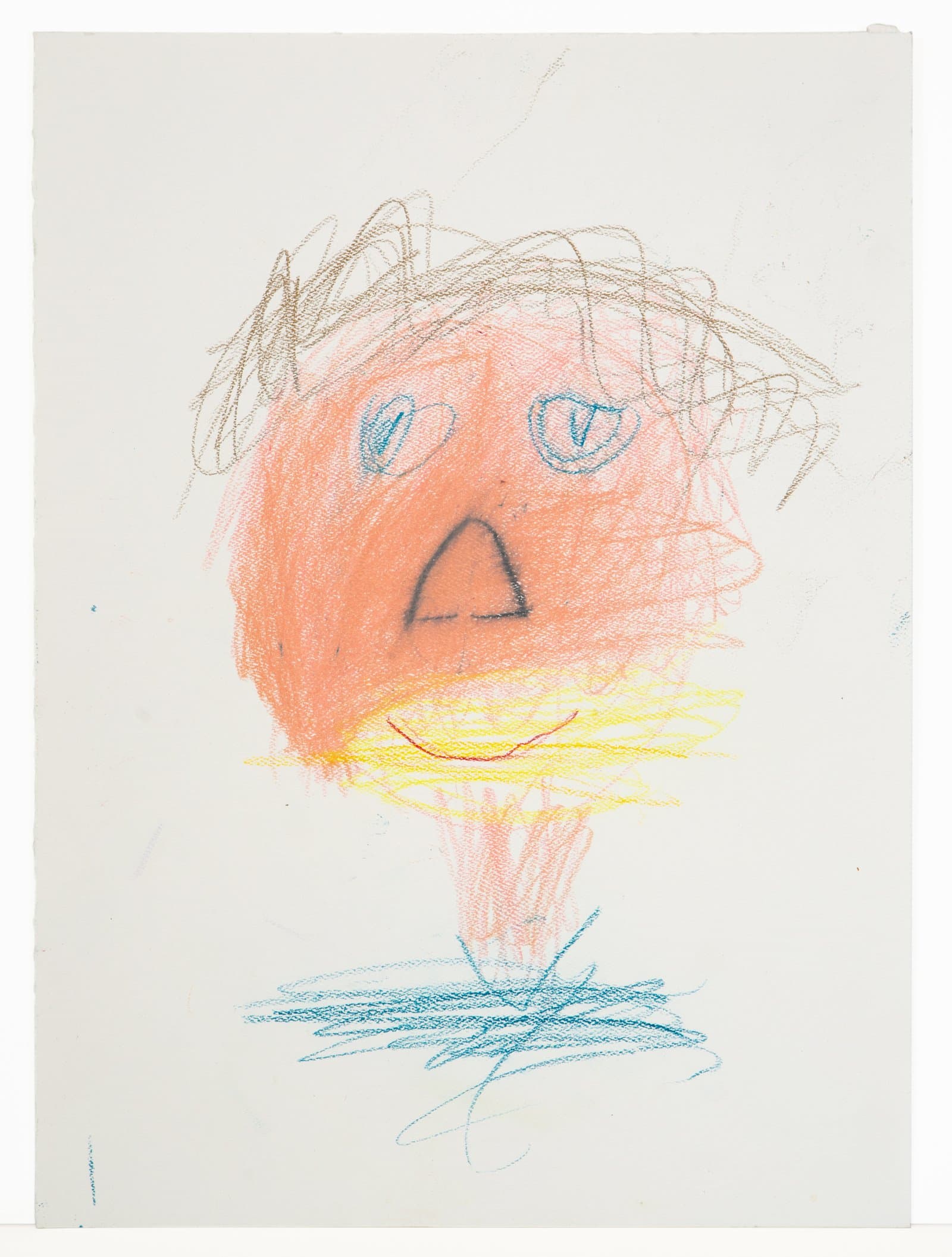 Crayon drawing of a face with orange shading, blue eyes, dark nose, red smile, brown scribbled hair, and blue crosshatching below.