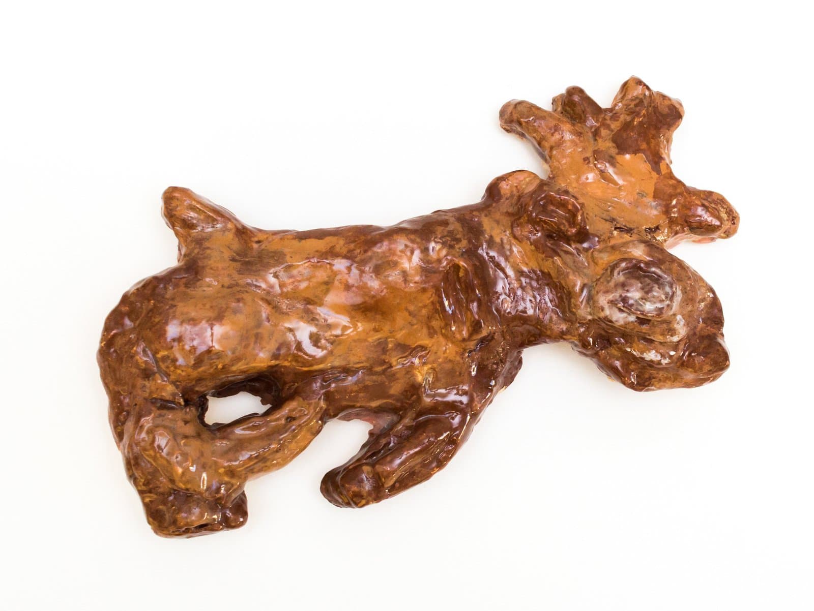 Glazed ceramic sculpture of a reclining deer or moose with antlers, in warm amber and brown tones, on white background.
