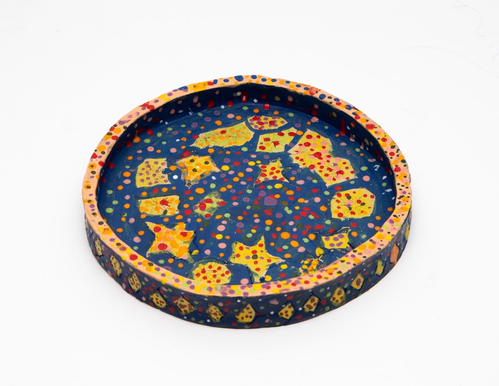 Ceramic bowl with navy blue interior decorated with yellow cheese-like shapes and colorful polka dots