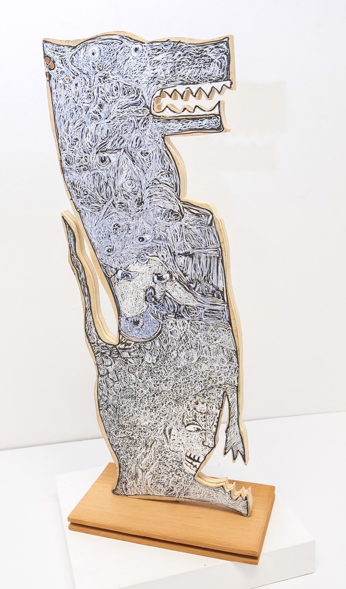 Sculptural drawing on wood showing fantastical creatures with intricate pen and ink details on shaped plywood base