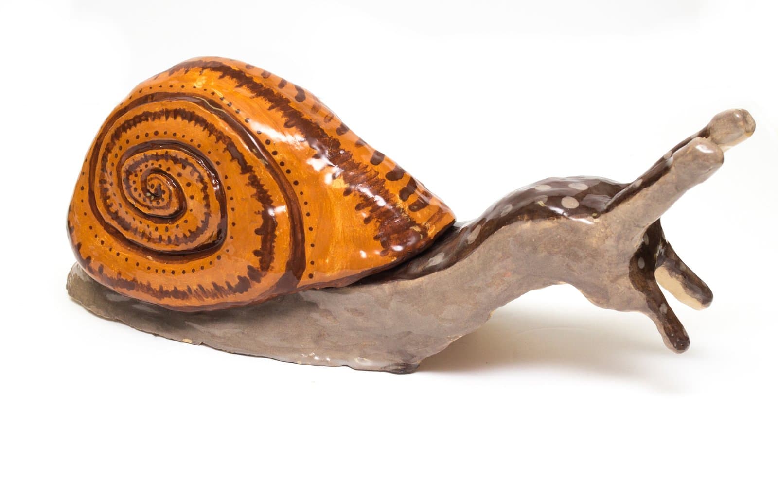 Glazed ceramic sculpture of a snail with a spiral orange-brown shell and gray-brown spotted body on white background.